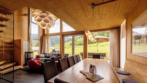 Ein geräumiger Essbereich mit einem langen Holztisch, mehreren Stühlen und einem großen Fenster mit Blick ins Freie.