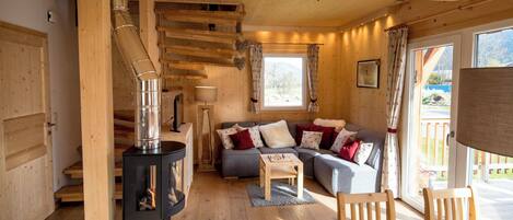 A cozy cabin interior with a fireplace, wooden furniture, and a window with a view.