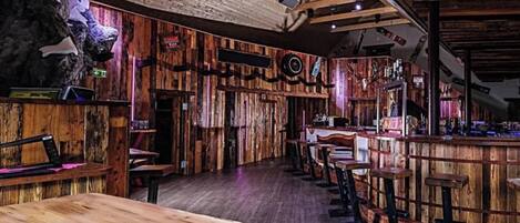 A rustic interior with wooden walls, a bar area, and seating.