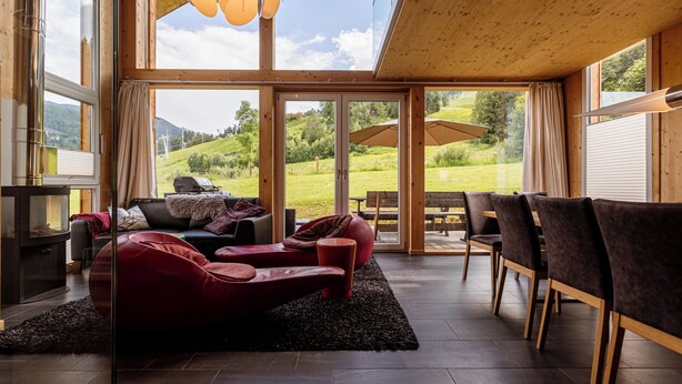 Ein modernes Wohnzimmer mit Kamin, einem roten Ledersofa und einem Essbereich mit Stühlen und Tisch.
