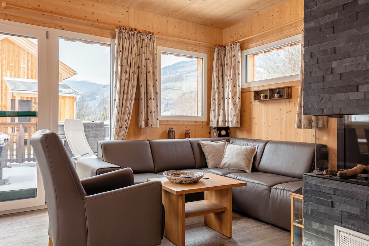 Acogedor interior de cabaña de madera con un sofá de cuero, una mesa de madera y una chimenea.