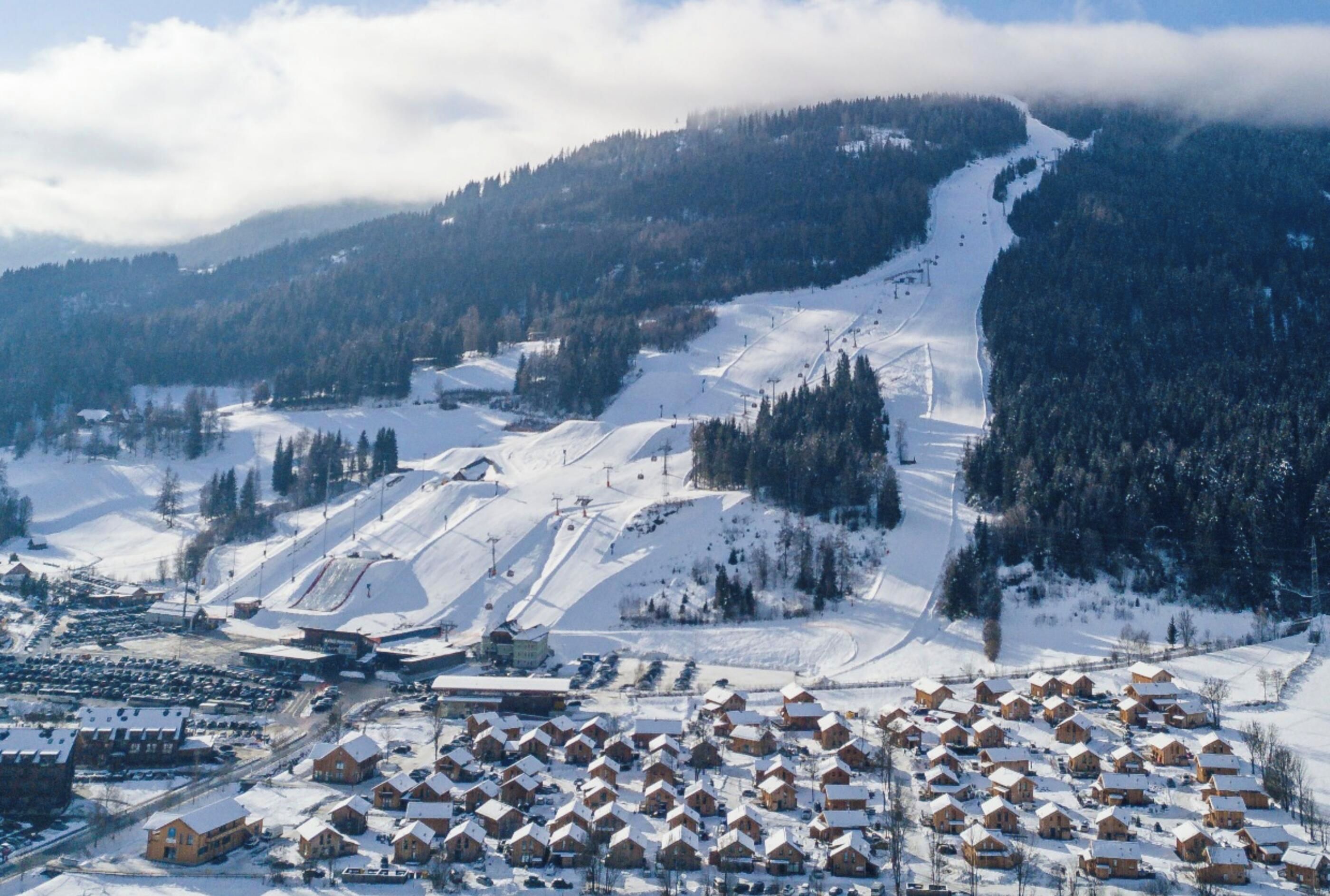 A snow-covered mountain with ski slopes and a small village with wooden houses.