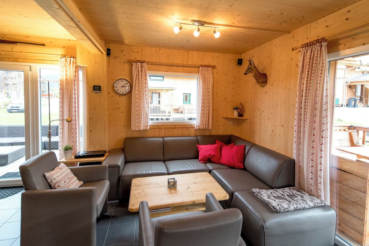 A cozy room with a brown leather sofa, a wooden coffee table, and a clock on the wall.