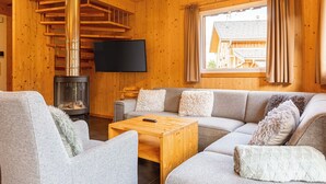 Ein gemütliches Blockhaus-Interieur mit Holzvertäfelung, einer Couch, einem Fernseher und einem Kamin.