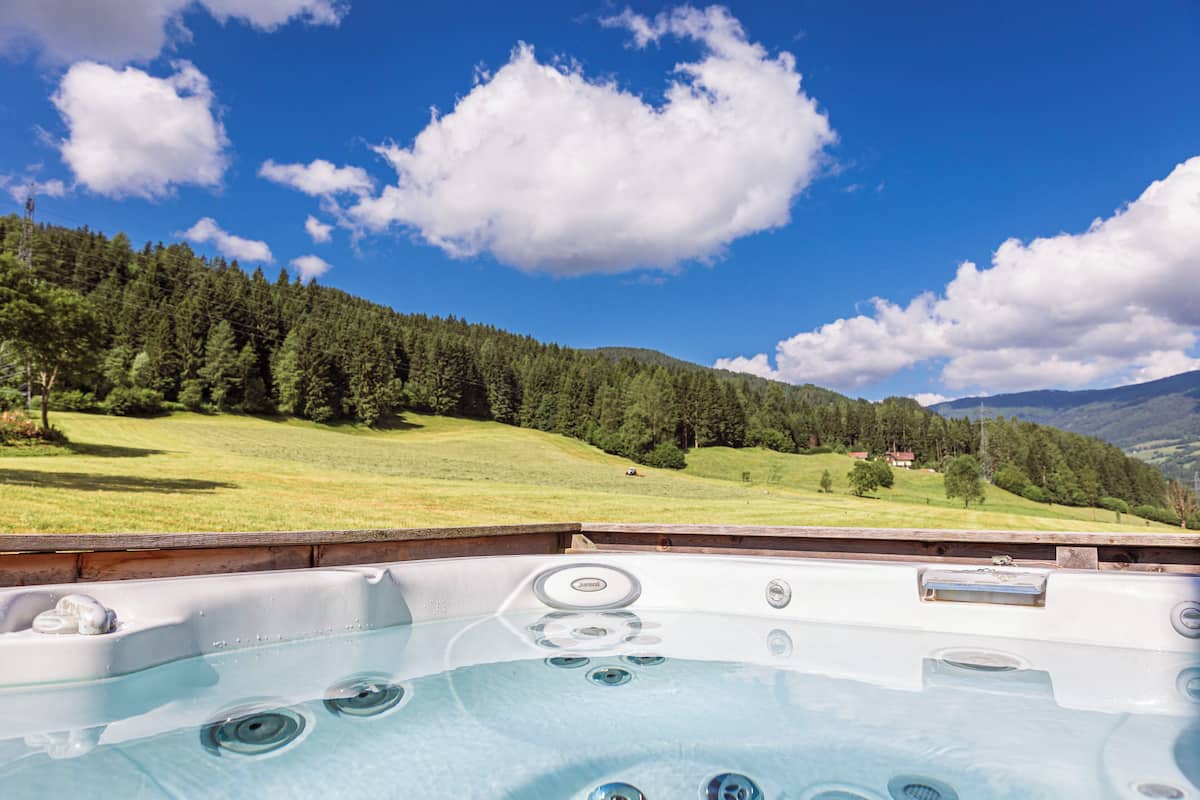 Un jacuzzi con vistas a una ladera verde y montañas al fondo.