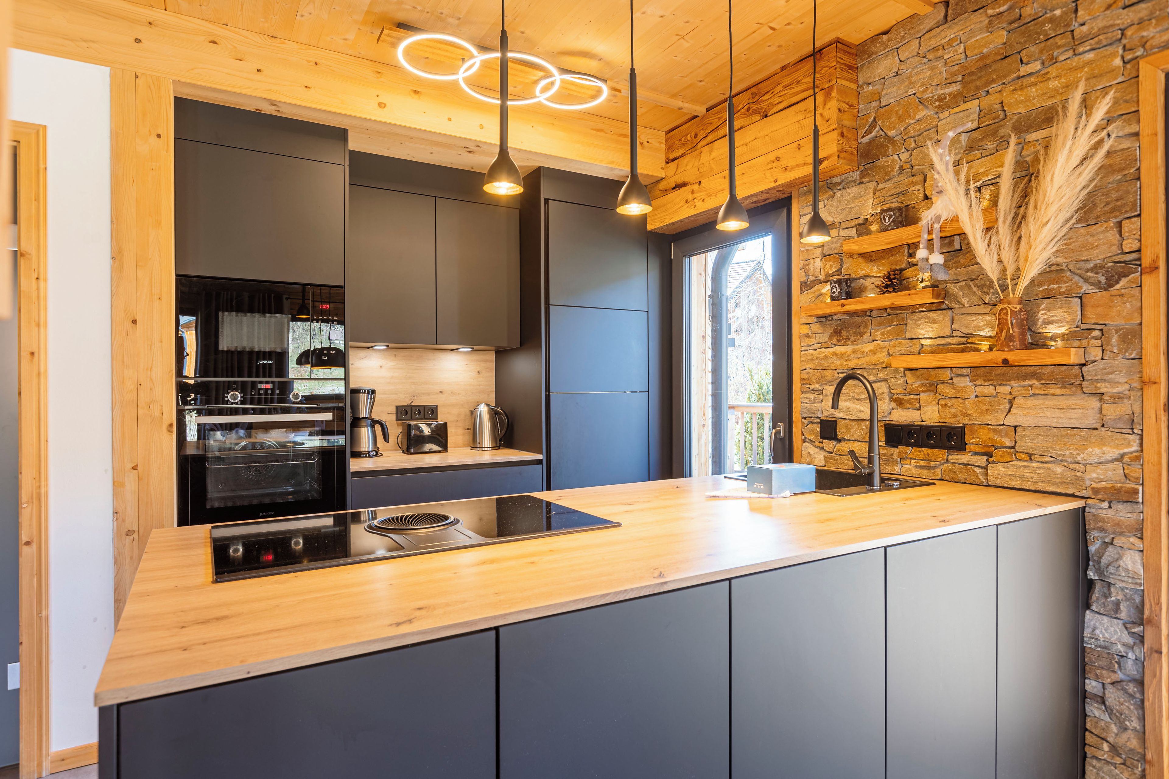 Een moderne keuken met een houten aanrecht, een ingebouwde oven en een spatwand van natuursteen.