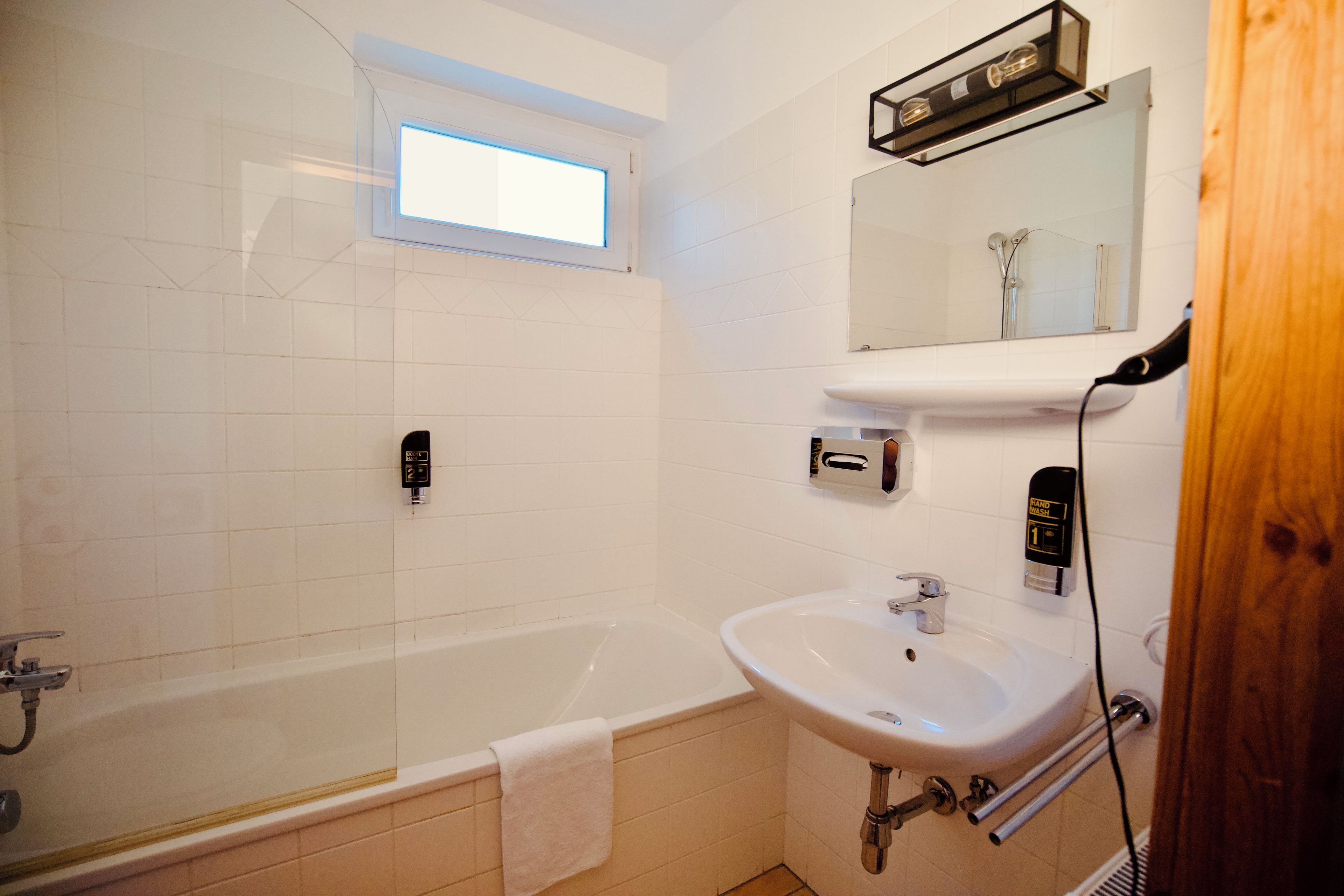 Une salle de bain équipée d’une baignoire, d’un lavabo, d’un sèche-mains et d’un miroir.