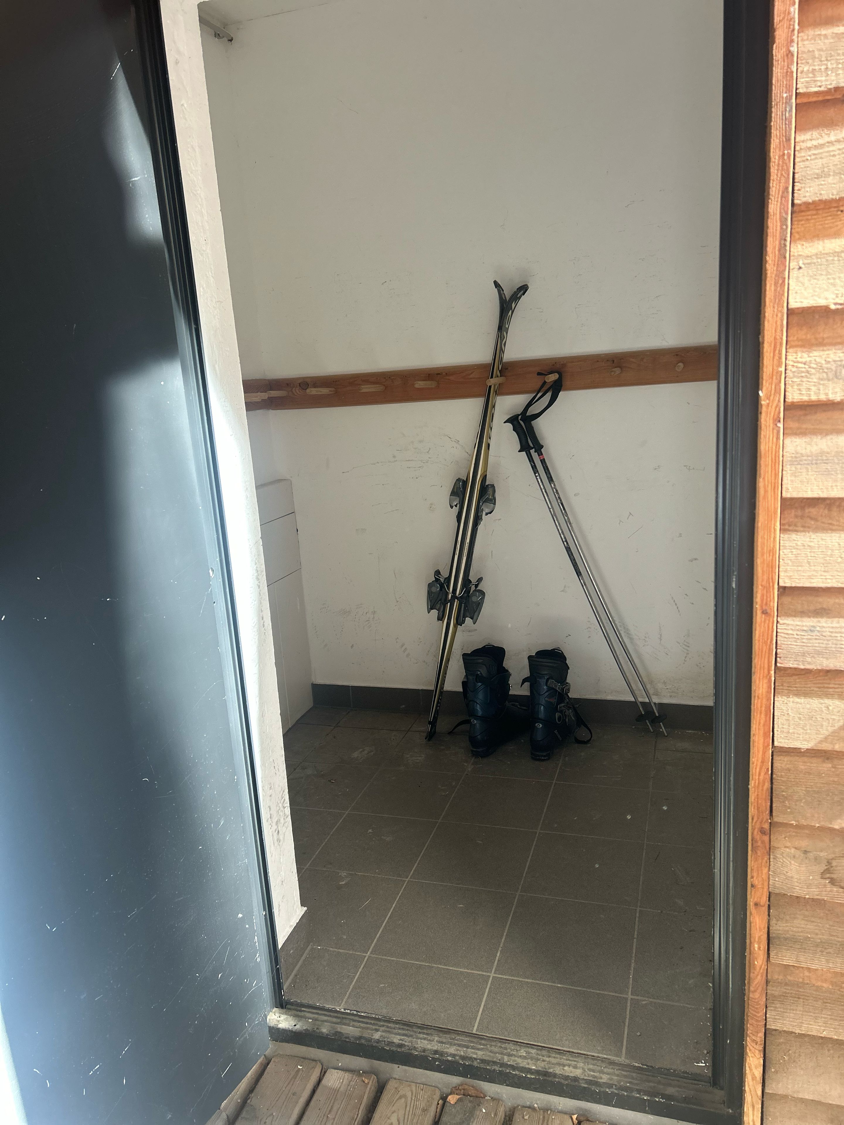 Una habitación con suelo de baldosas, techo con vigas de madera y un marco de puerta.