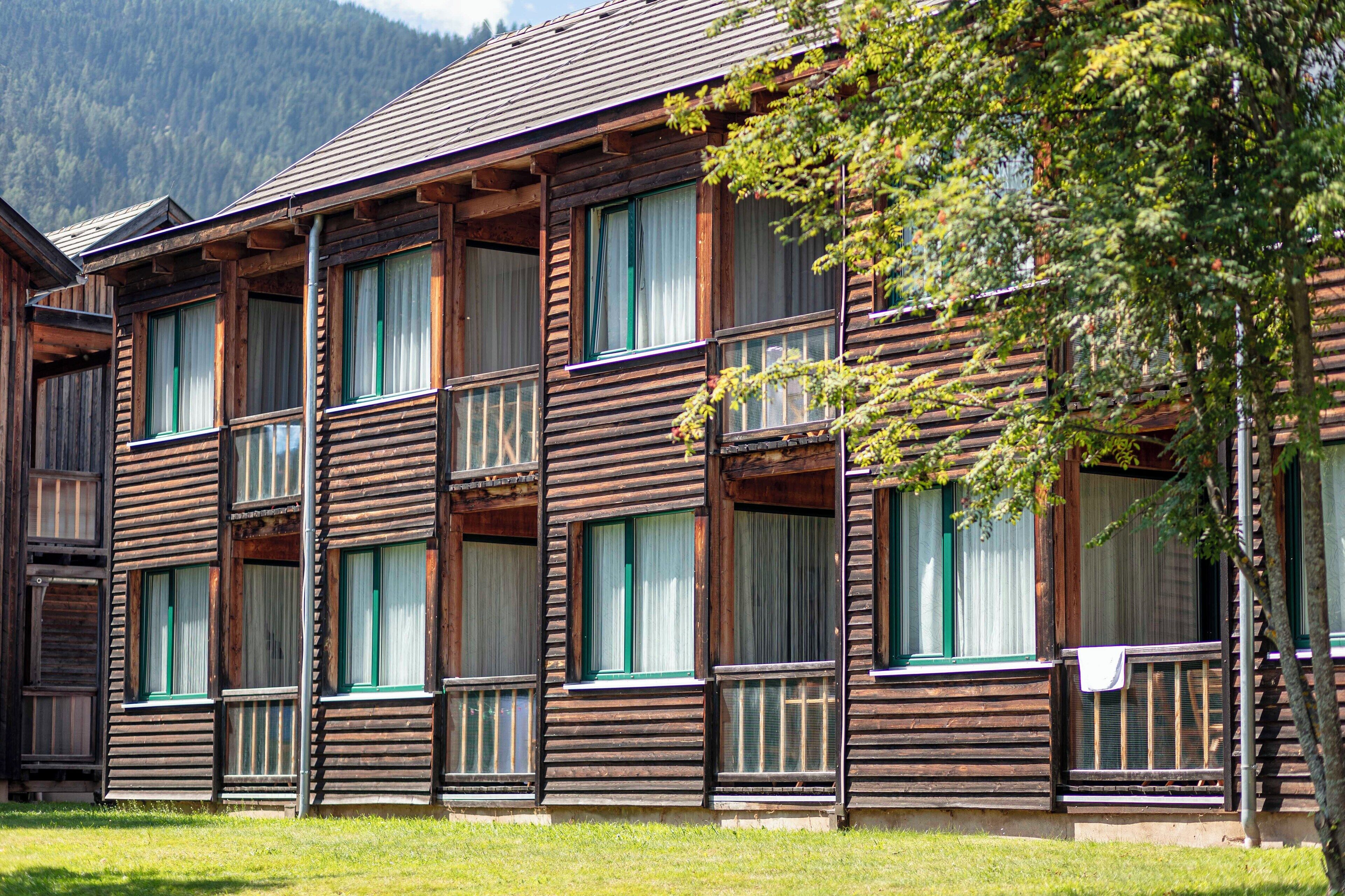 Un immeuble en bois à plusieurs étages, doté de balcons et de grandes fenêtres, qui ressemble probablement à un hôtel ou à une maison d’hôtes.