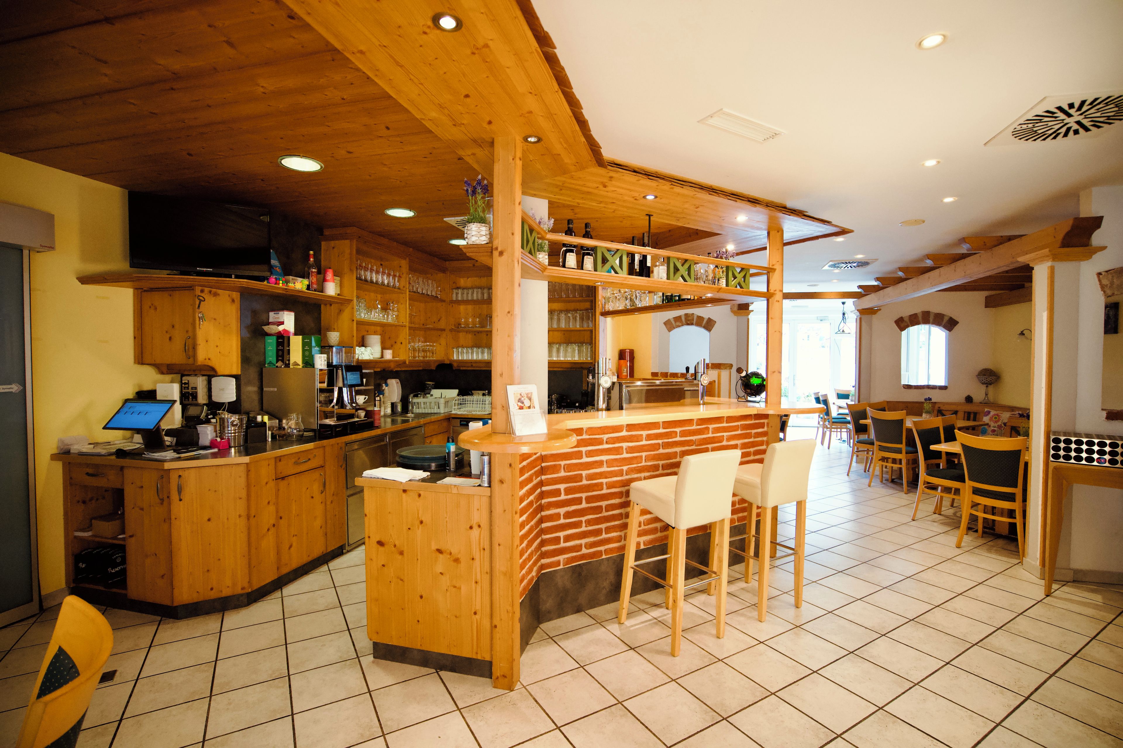 Ein Restaurant mit Barbereich, Holzmöbeln und Fliesenboden.