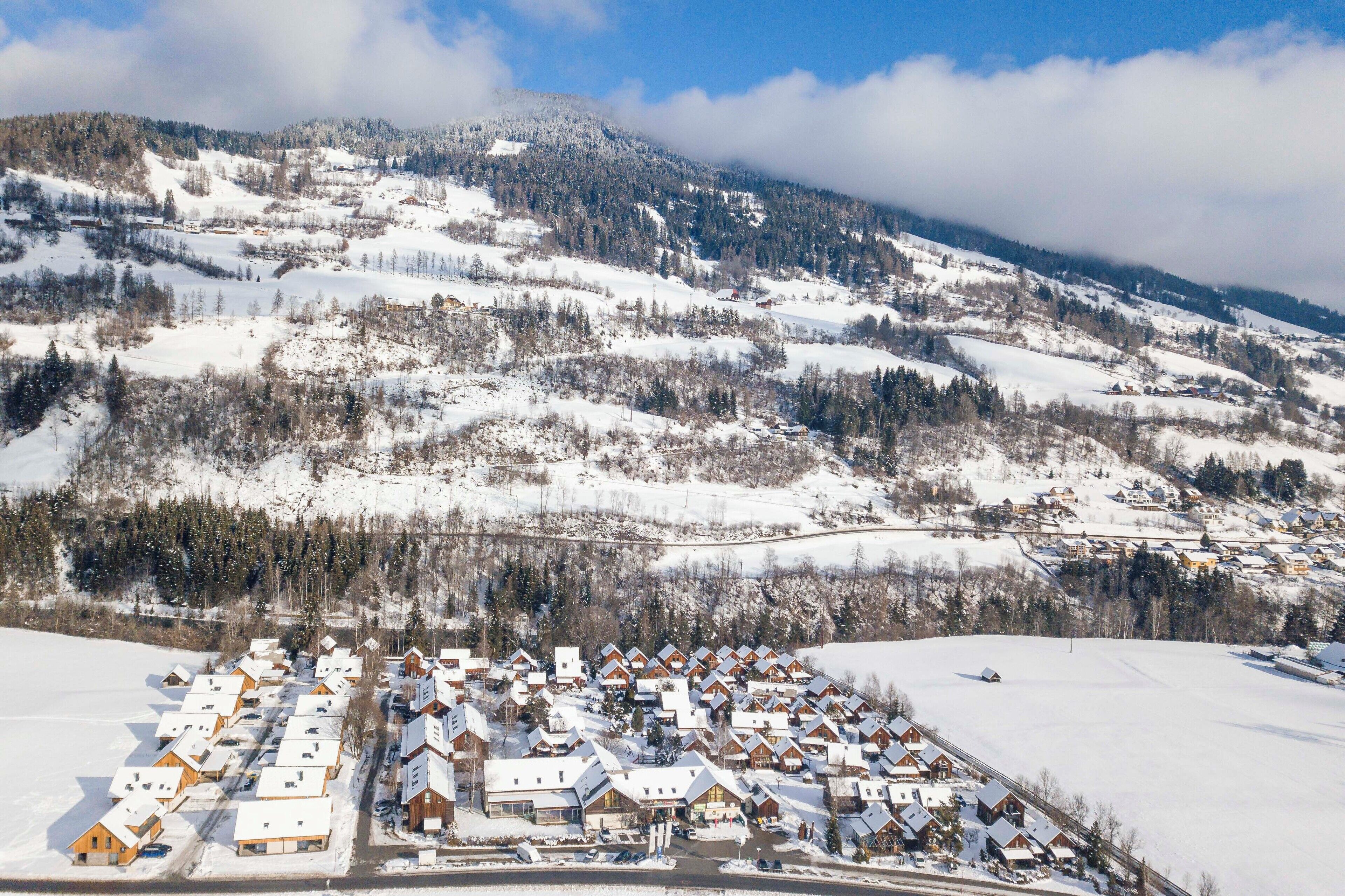 Un pueblo cubierto de nieve con casas de madera y una montaña al fondo.