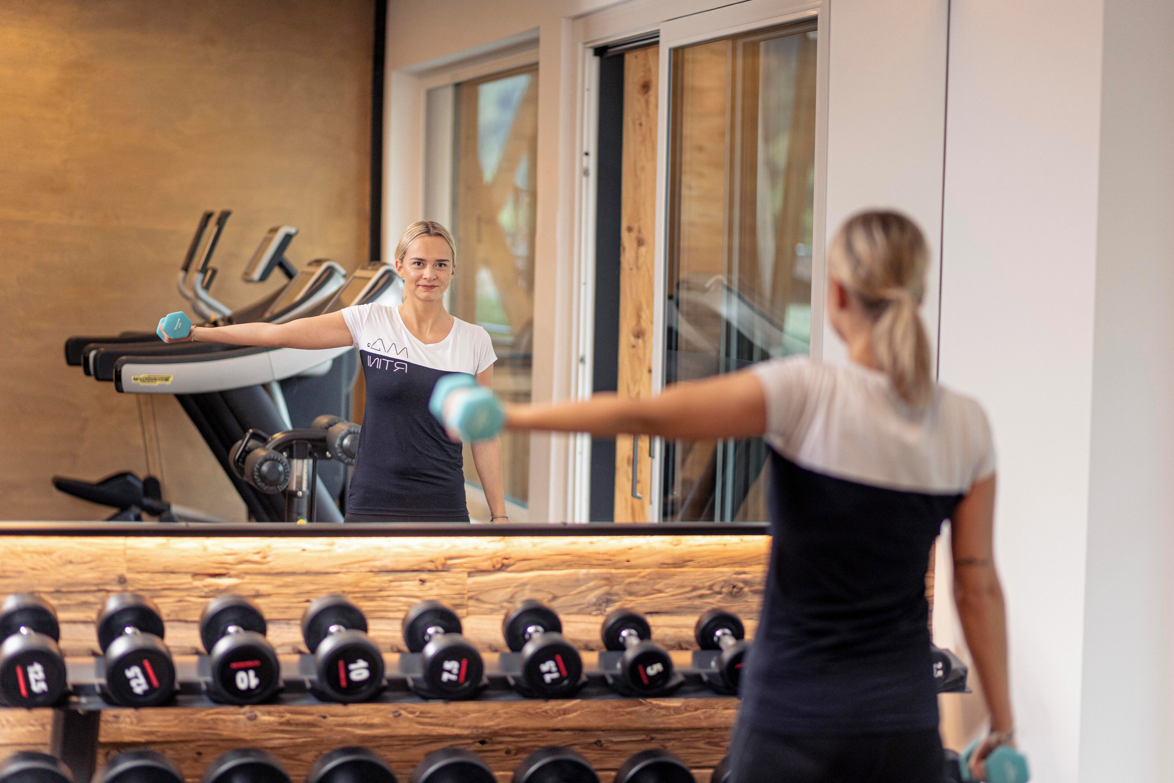 Un gimnasio con equipo de ejercicio, incluyendo cintas de correr y mancuernas.
