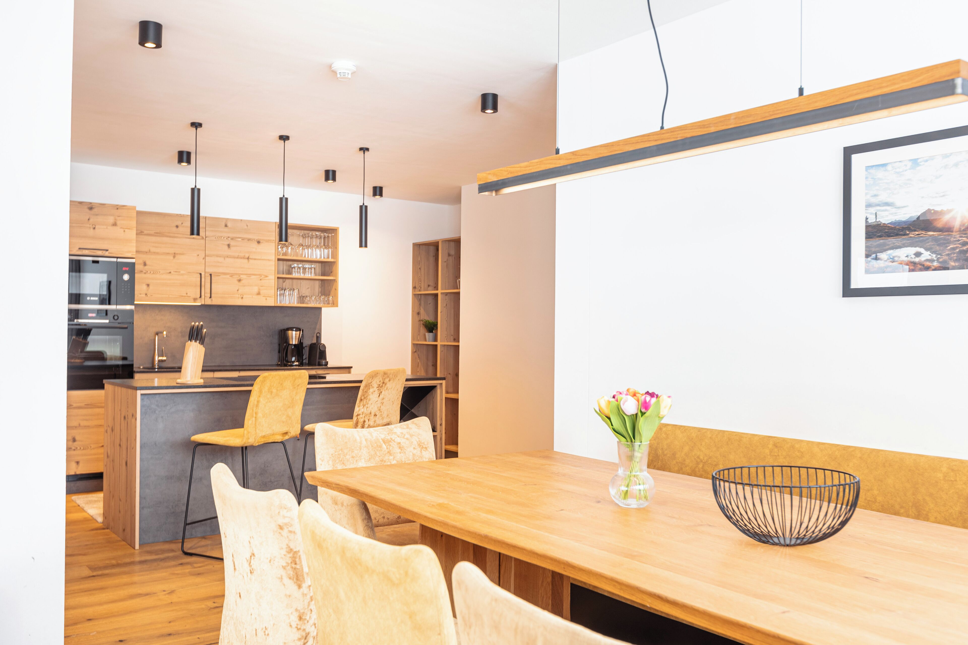 Une cuisine moderne avec des meubles en bois, un îlot central et des luminaires suspendus.