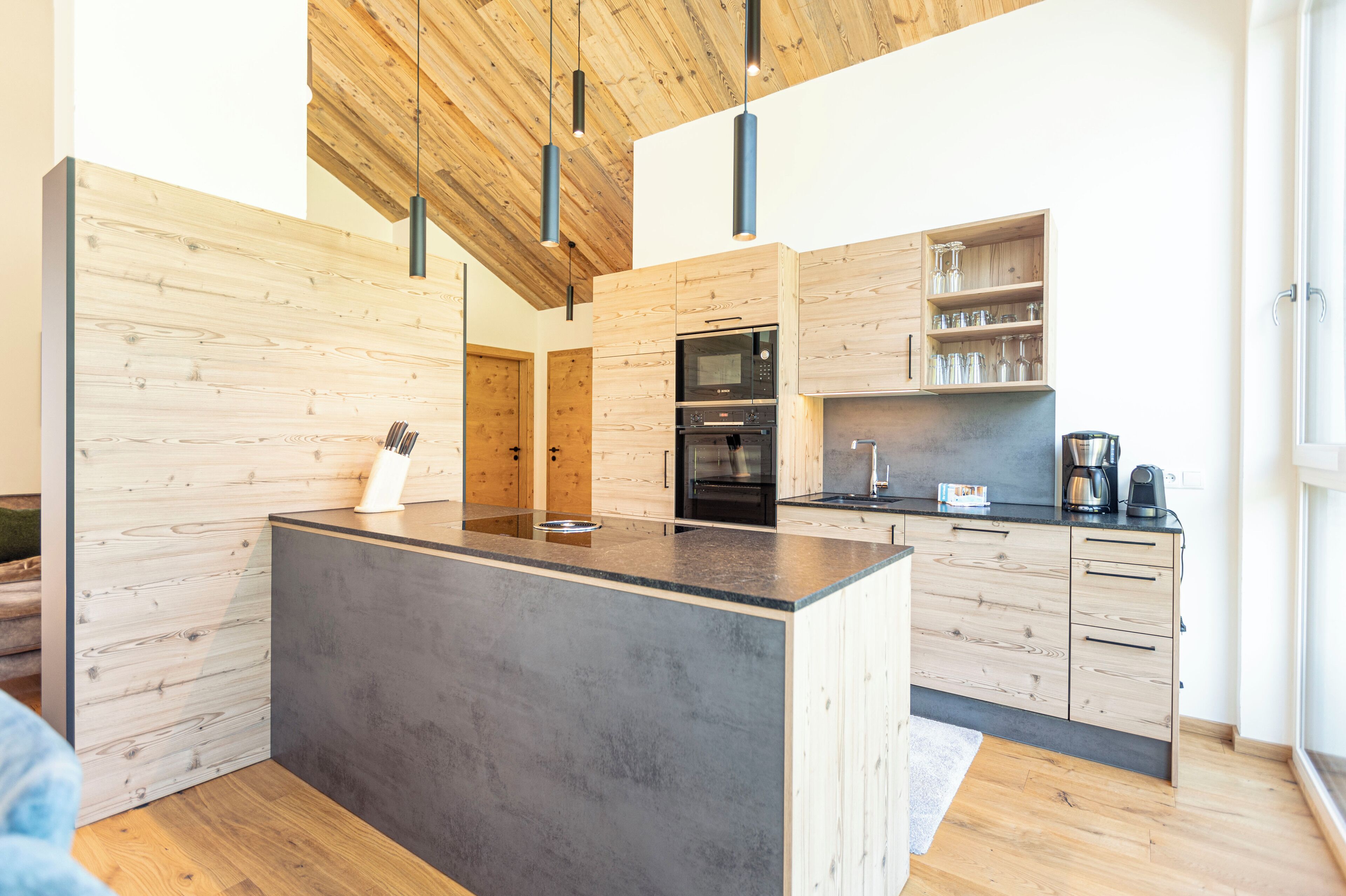 A modern kitchen with wooden cabinetry, a central island, and built-in appliances.