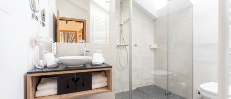 A modern bathroom with a glass-enclosed shower, a wooden vanity with a sink, and a large mirror.