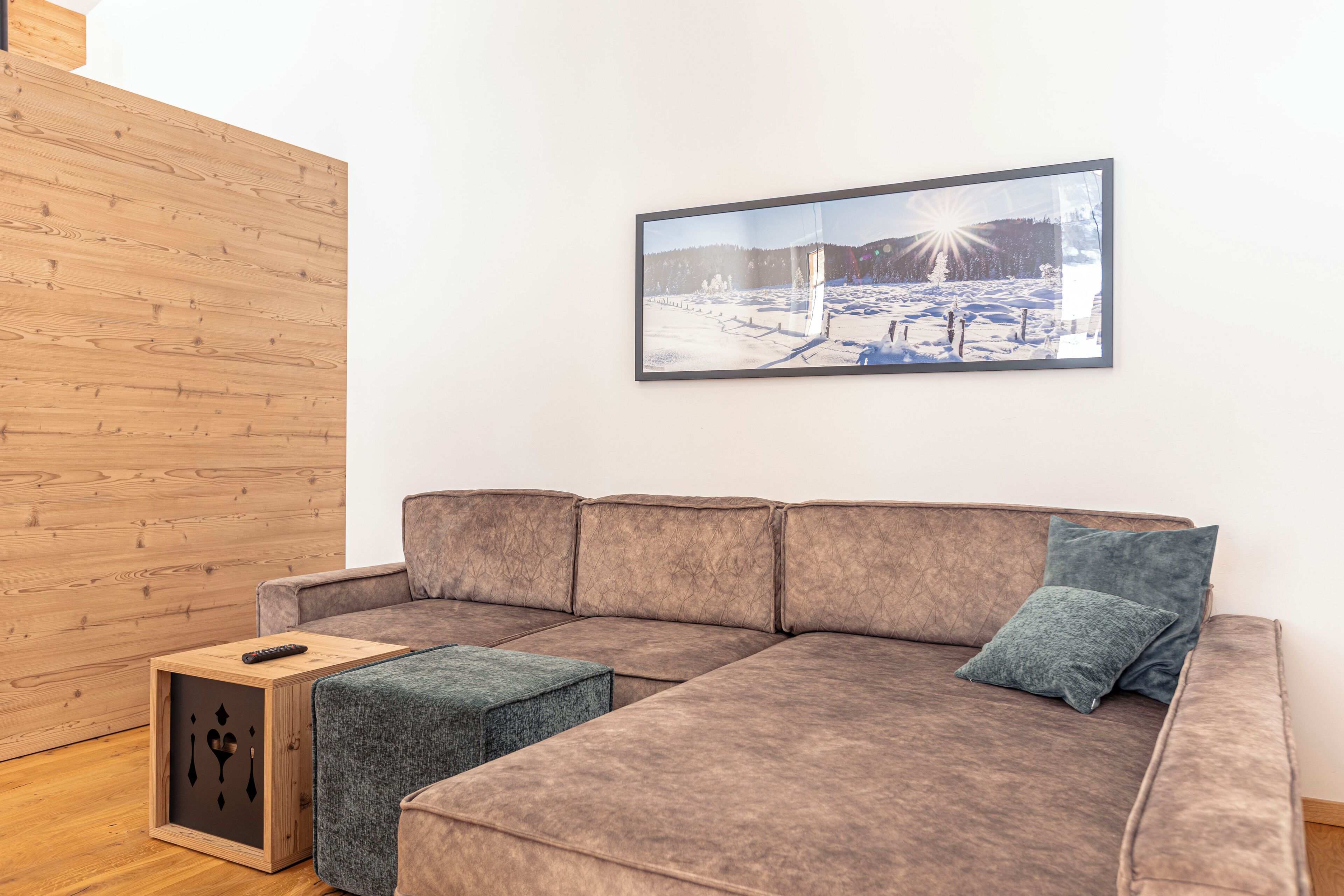 A modern living room with a sectional sofa, a small ottoman, and a framed picture on the wall.