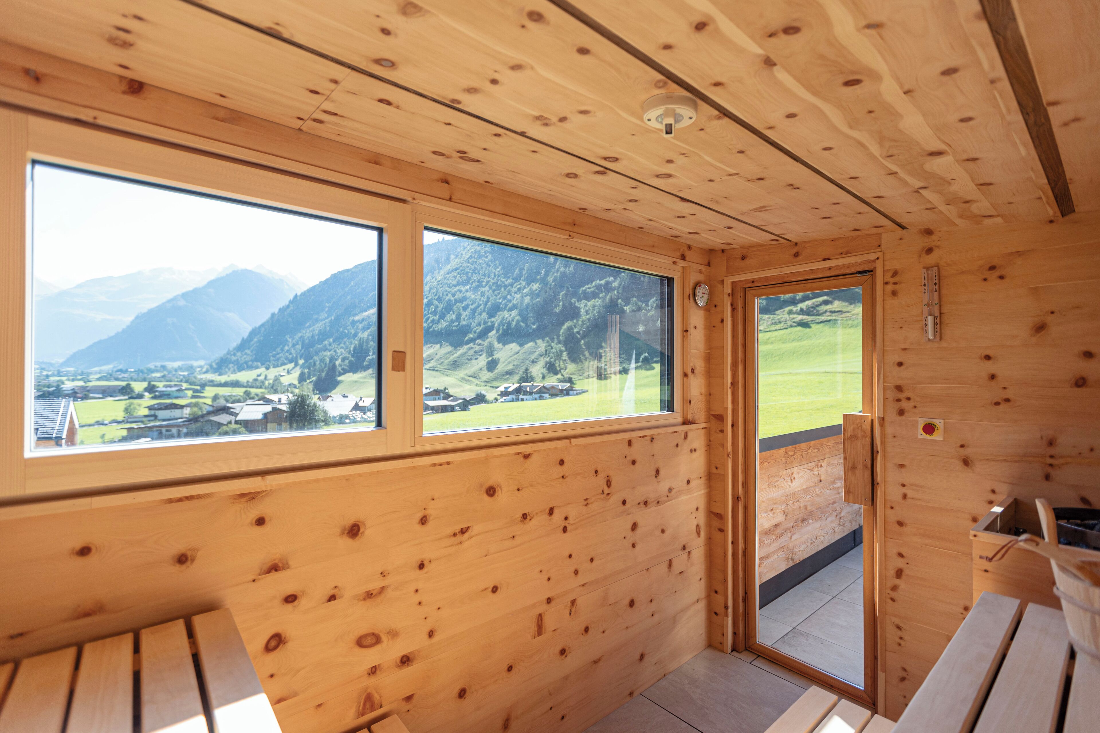 Una cabaña de madera con ventanas amplias que ofrece vistas a un paisaje montañoso.