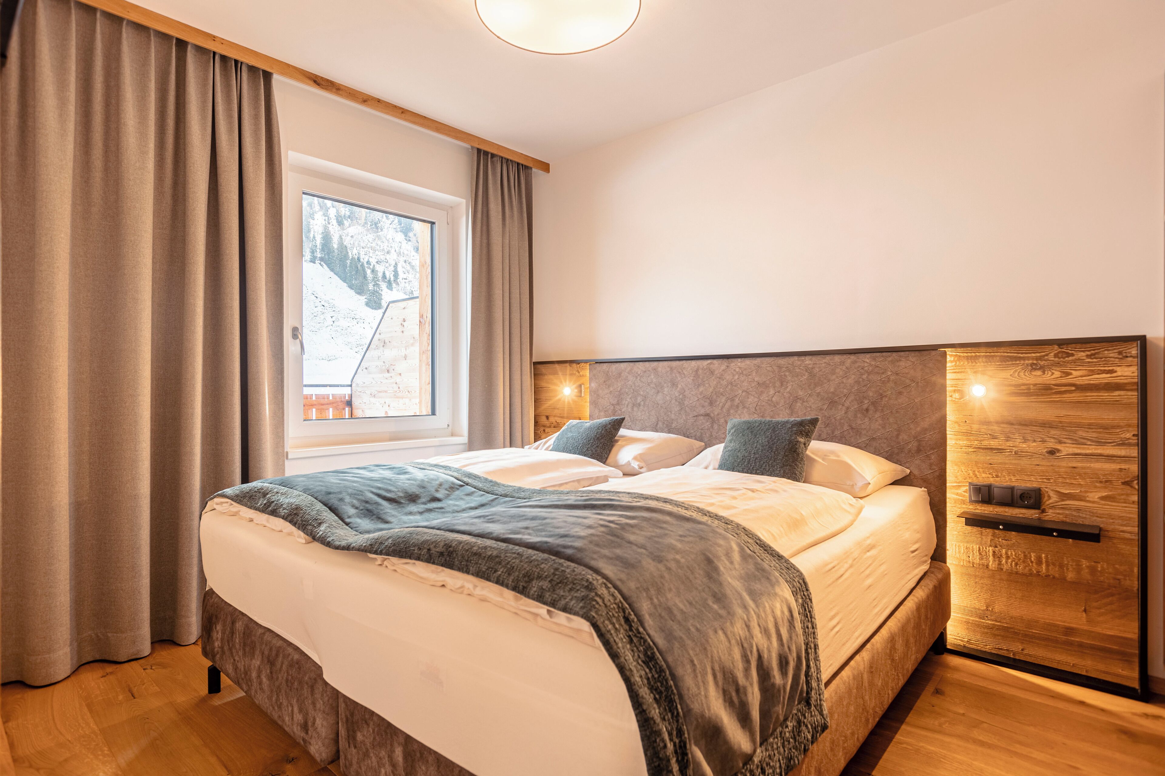 Un dormitorio con una cama grande, cabecera de madera y una ventana con cortinas.