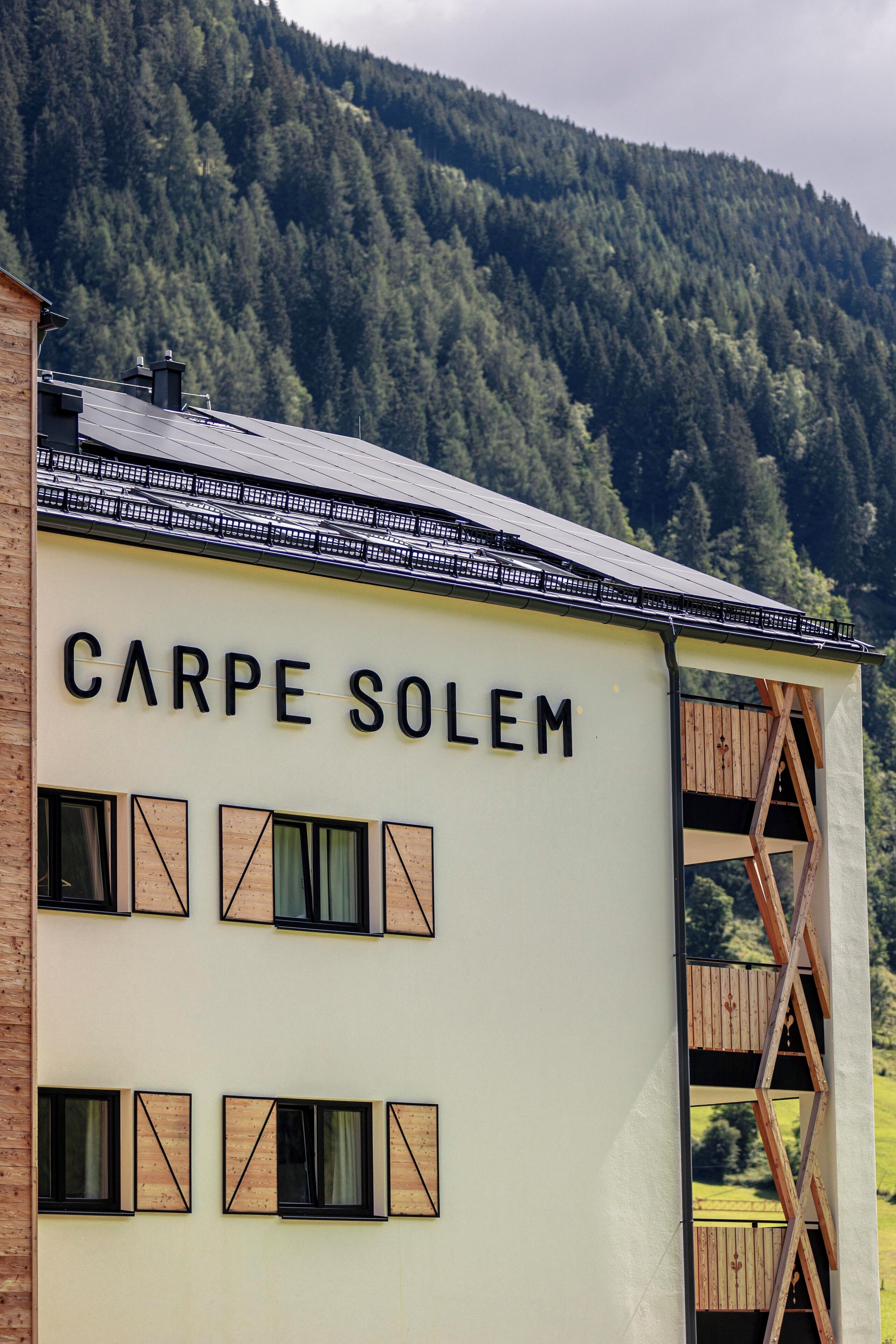 Un bâtiment sur lequel on peut lire l’inscription « CARPE SOLEM » et qui possède un balcon en bois.