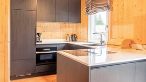 Una cocina moderna con gabinetes oscuros, una isla grande y un ventanal con vistas a zonas verdes.