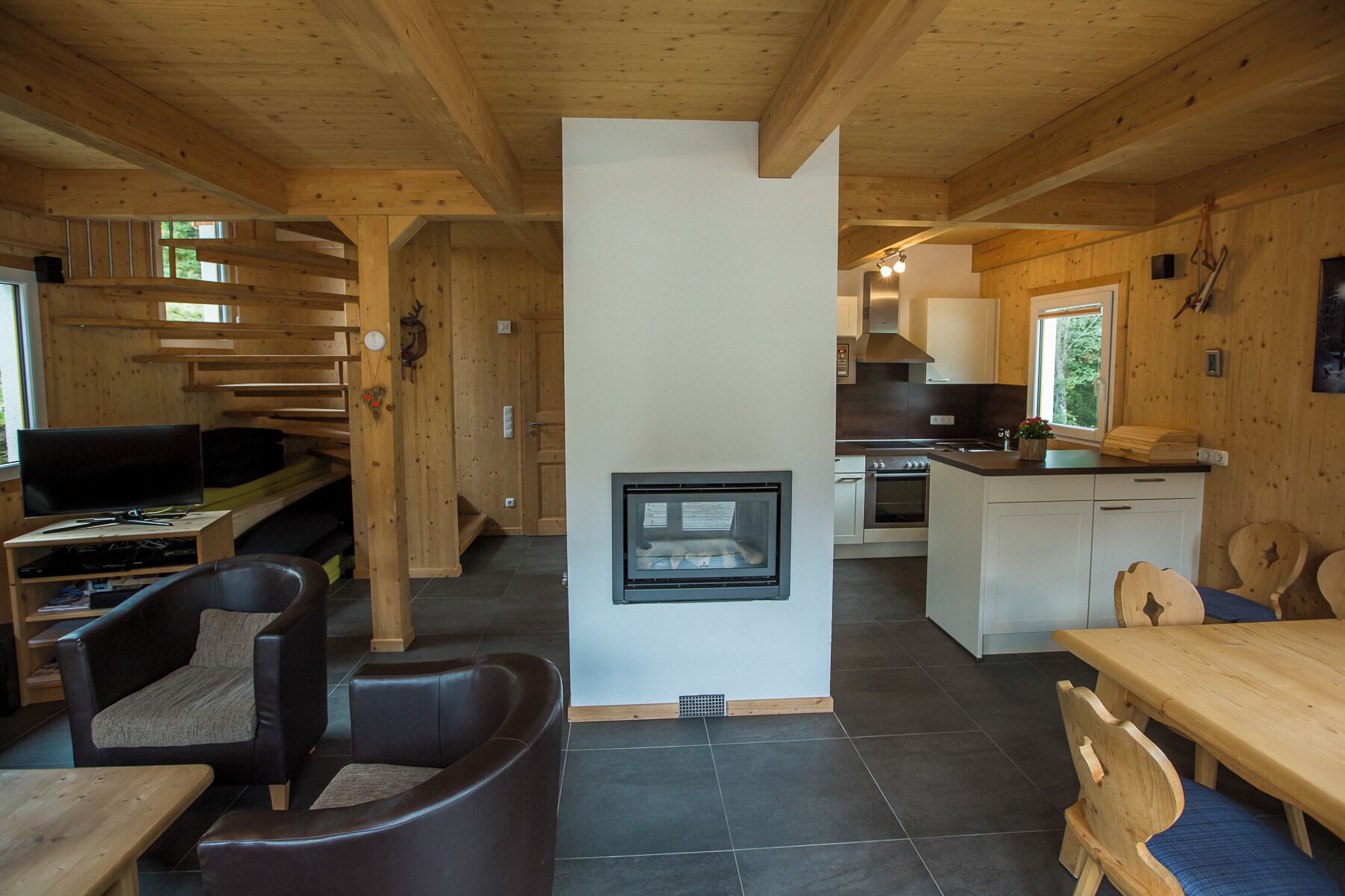 Ein Holzinnenraum mit Kamin, einer Küche und Sitzbereichen.