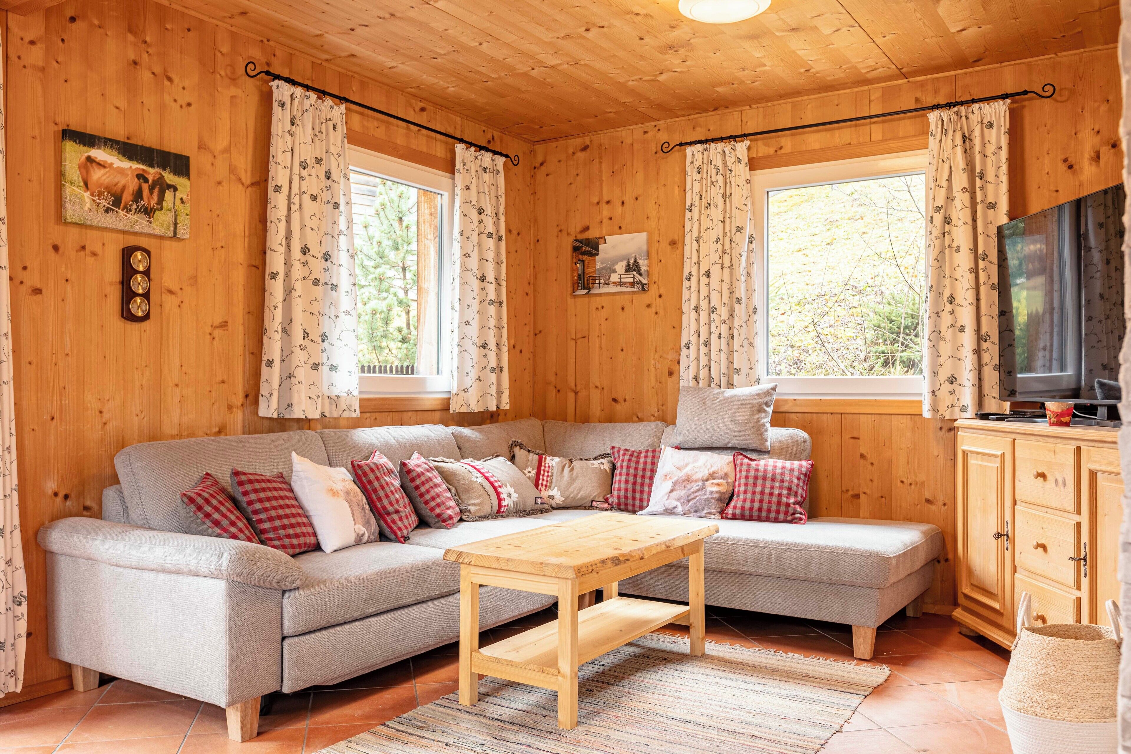 Un intérieur de chalet chaleureux avec un canapé, une table en bois et un téléviseur.