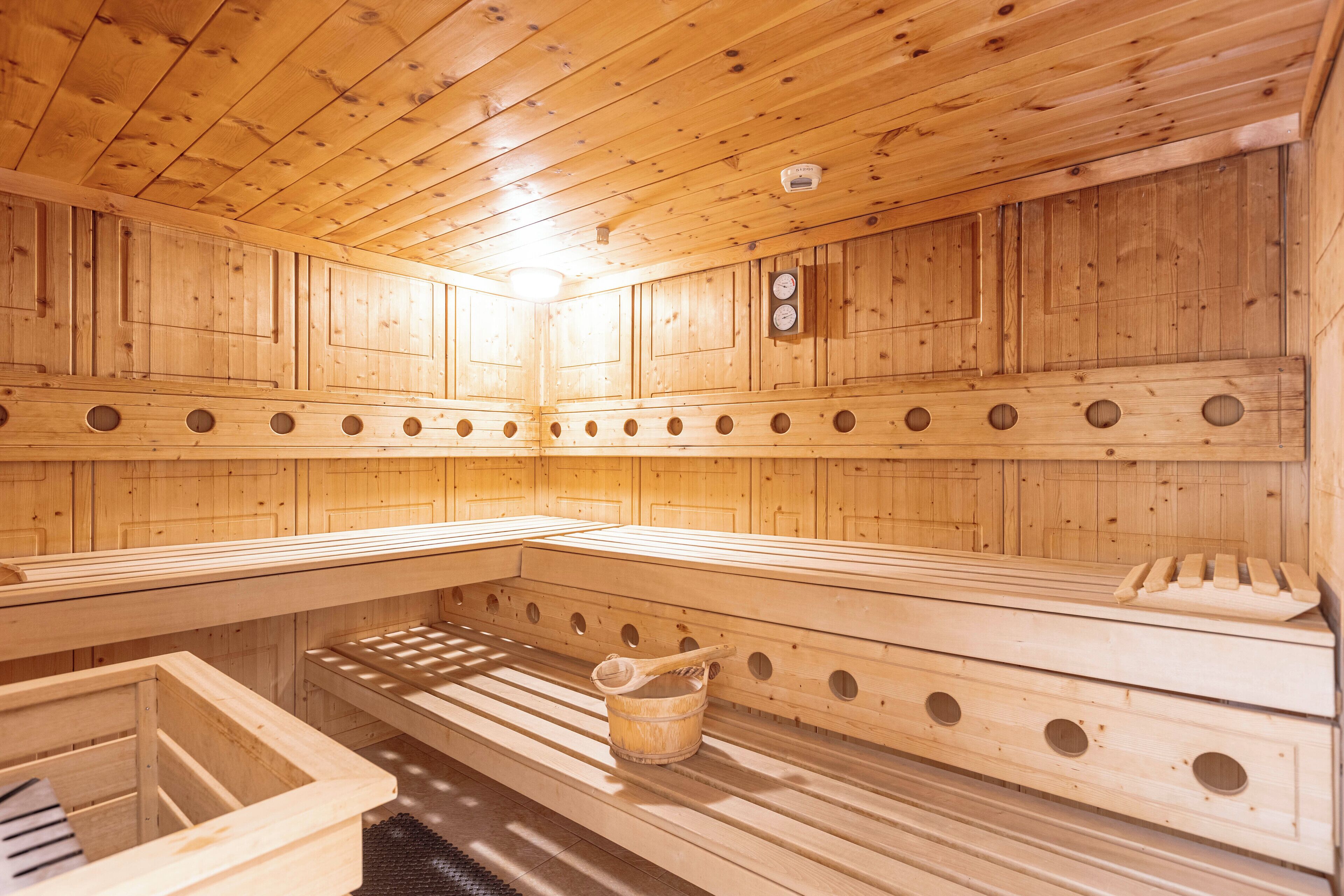 A wooden sauna with benches and a bucket.