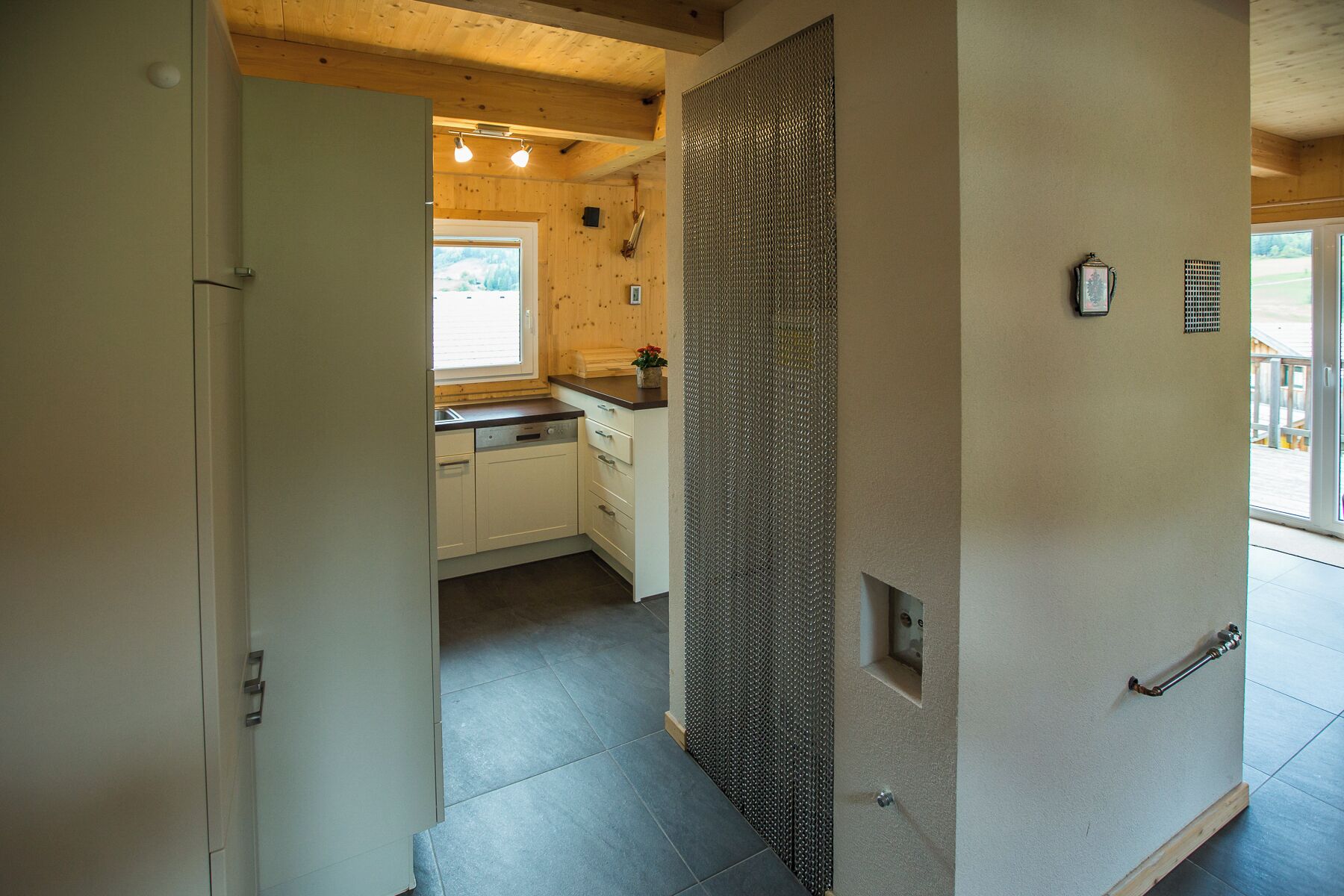 Una cocina moderna con armarios blancos, techo de madera y un amplio ventanal.