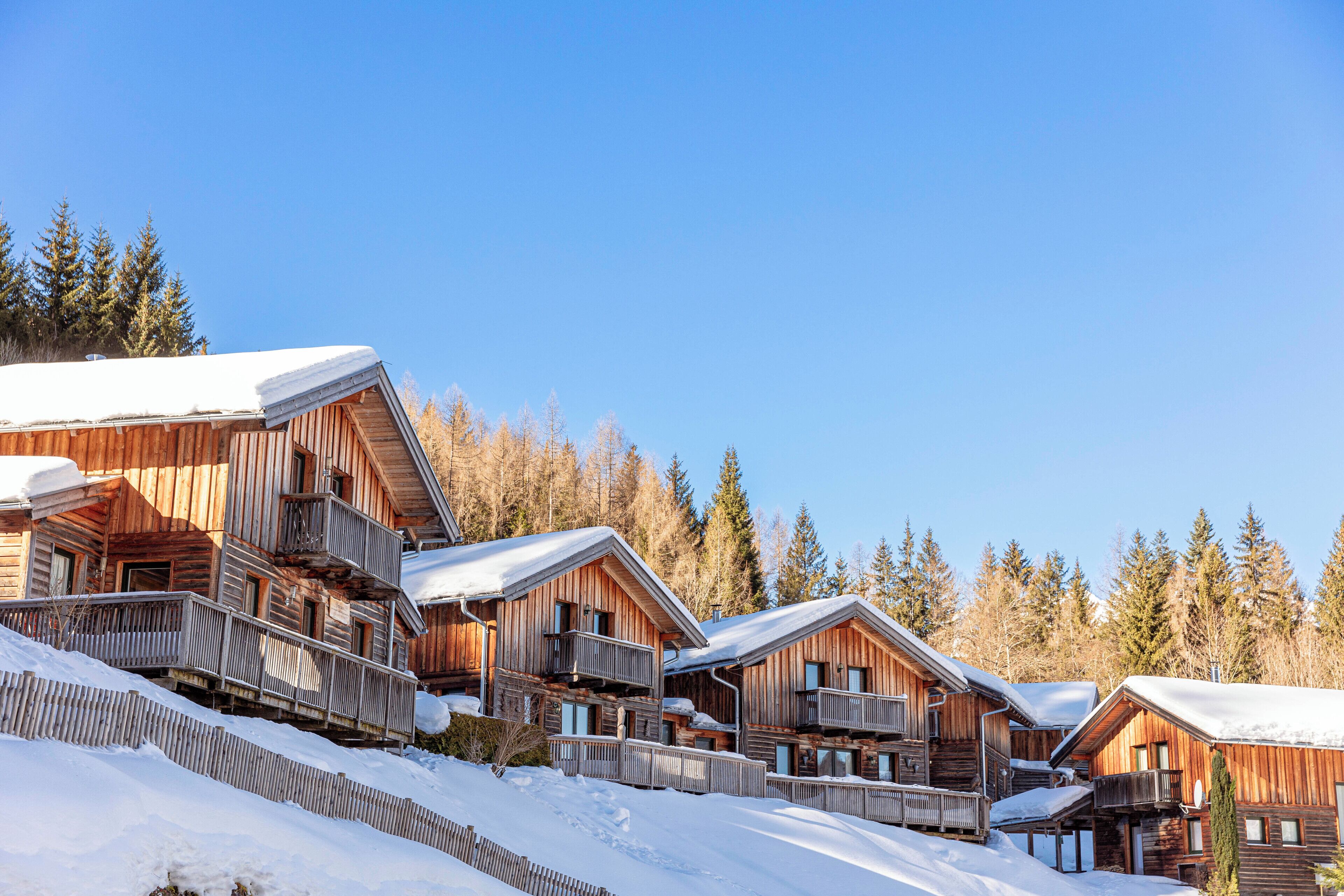 Eine Reihe von Holzhütten mit Balkonen, umgeben von Schnee und Bäumen.