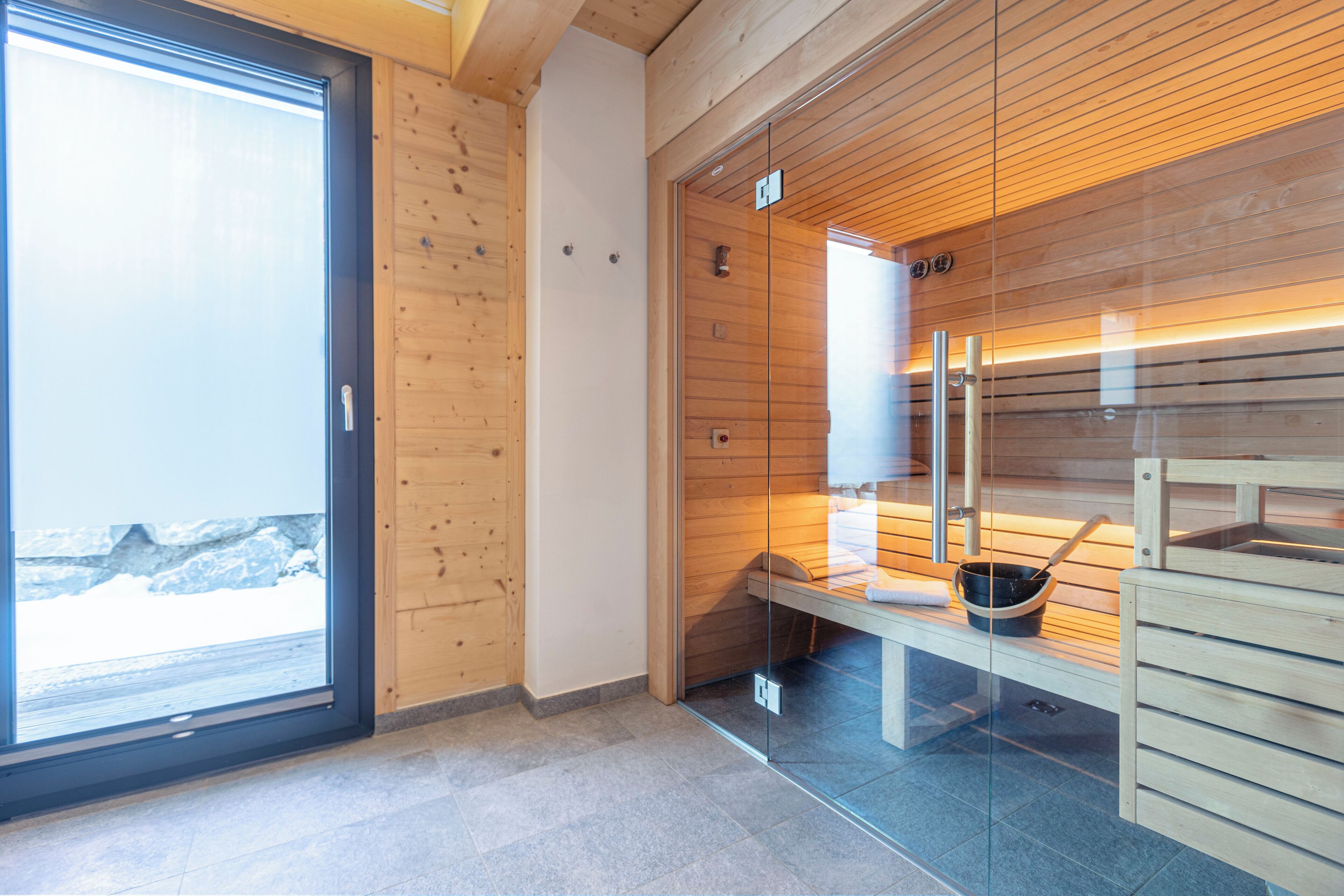 Un sauna moderno con paredes de madera, puerta de cristal y un banco.