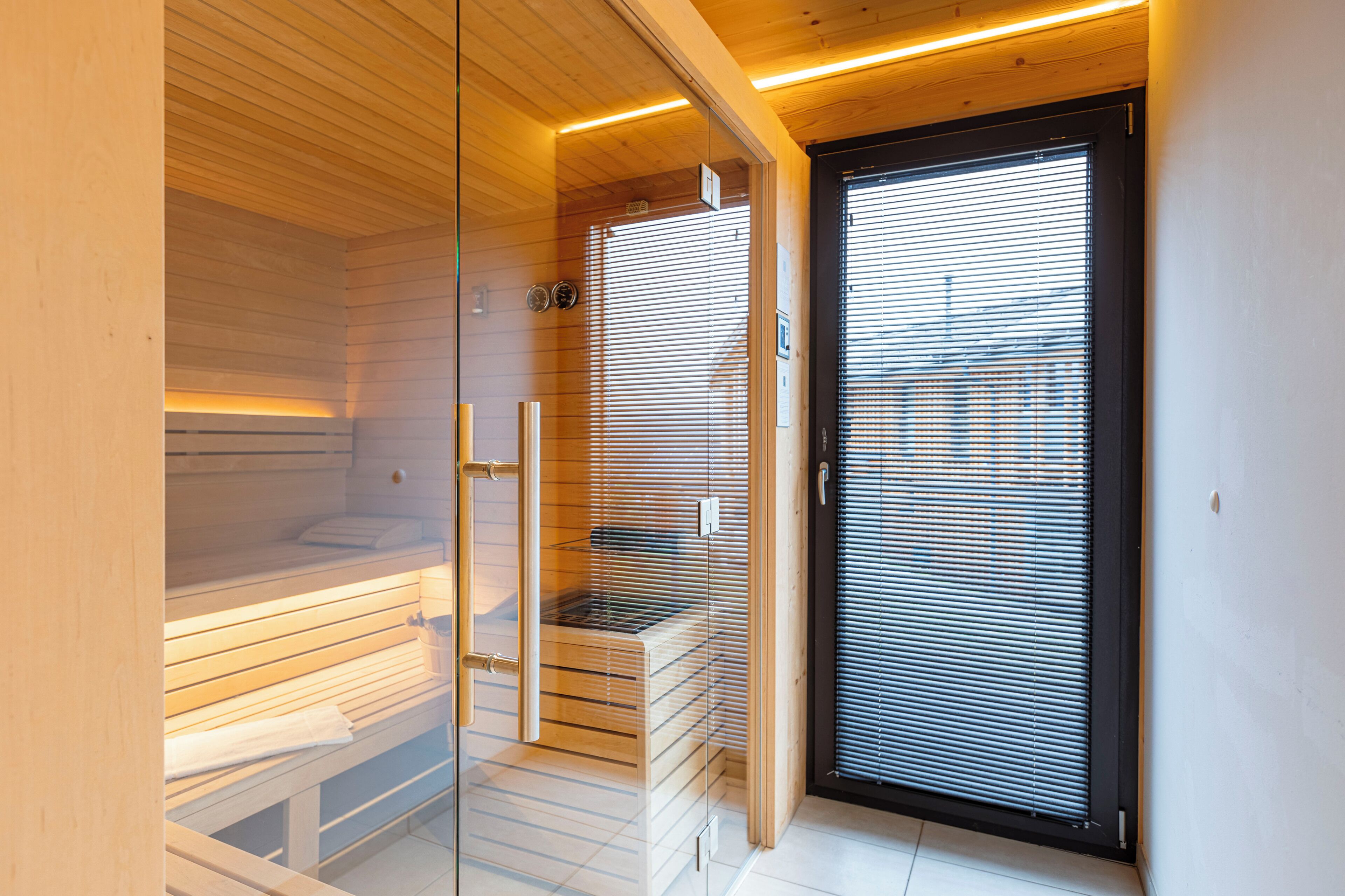 Una sauna con panche di legno e una porta in vetro.