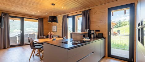 Una cocina moderna con una isla central, techo de madera, ventanas grandes y vistas al exterior.