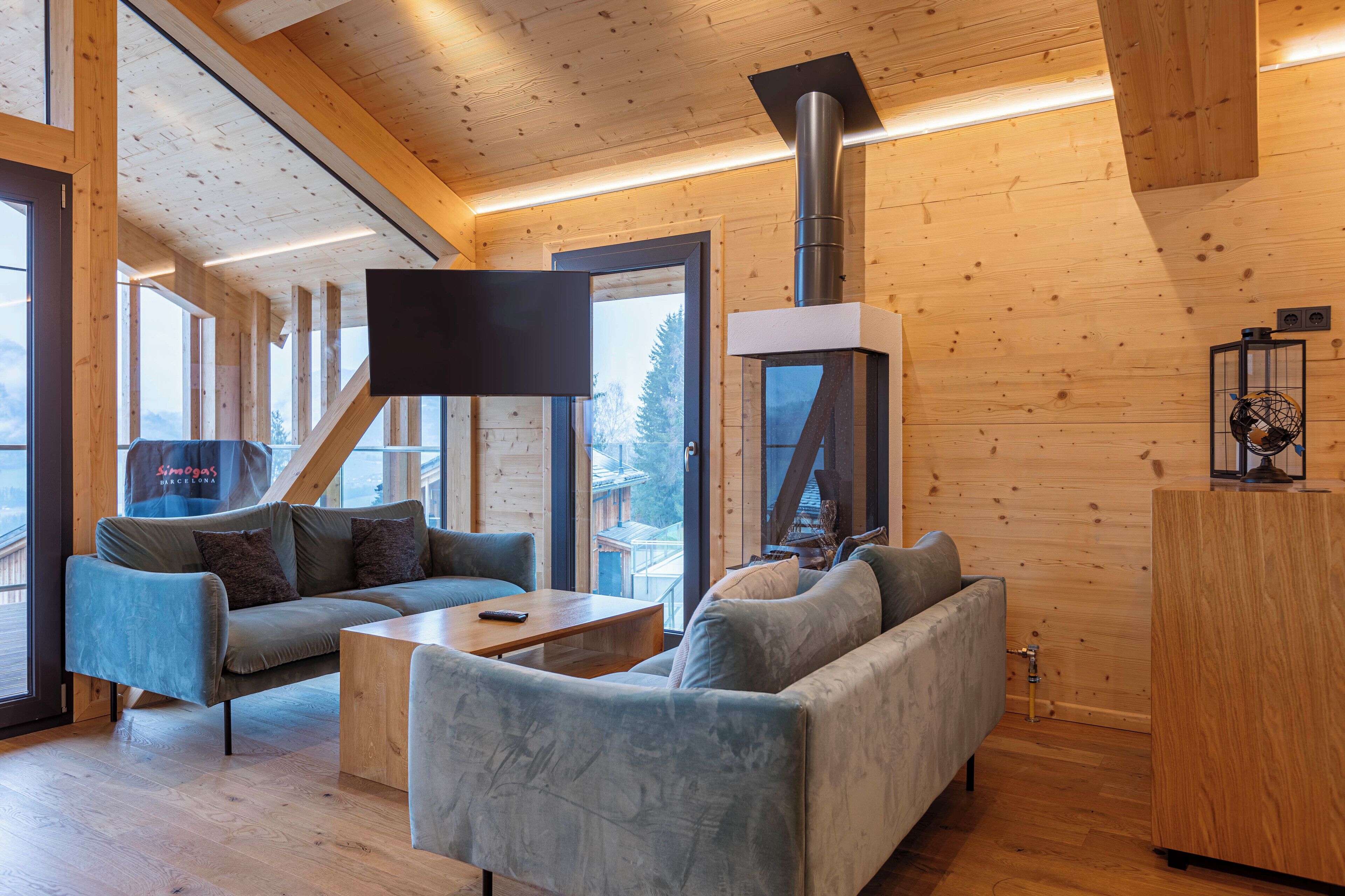 Ein modernes Interieur einer Blockhütte mit einer Couch, einem Couchtisch und einem Kamin.