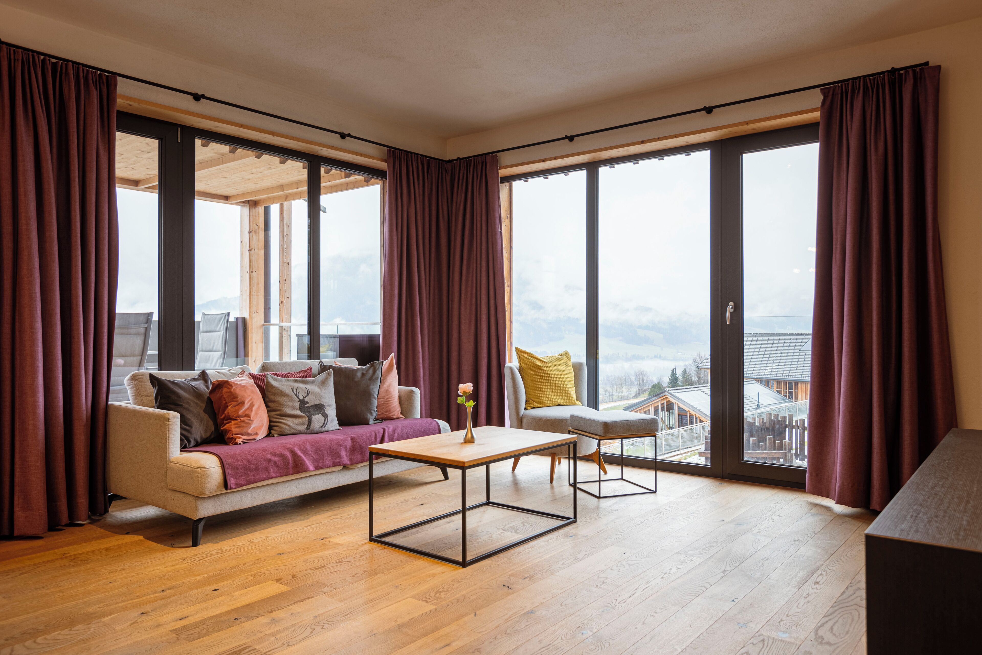 Un salon moderne avec un canapé, une table basse et une vue sur le paysage urbain, grâce à de grandes fenêtres.