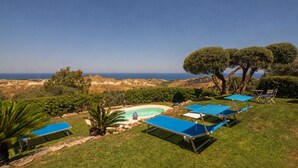 Un espace piscine avec des chaises longues et vue sur l’océan.