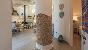 A room with a stone column, a dining area with chairs and a table, and a wall with decorative masks. - Villa Acquaro Santa Caterina  (Santa Caterina dello Ionio)