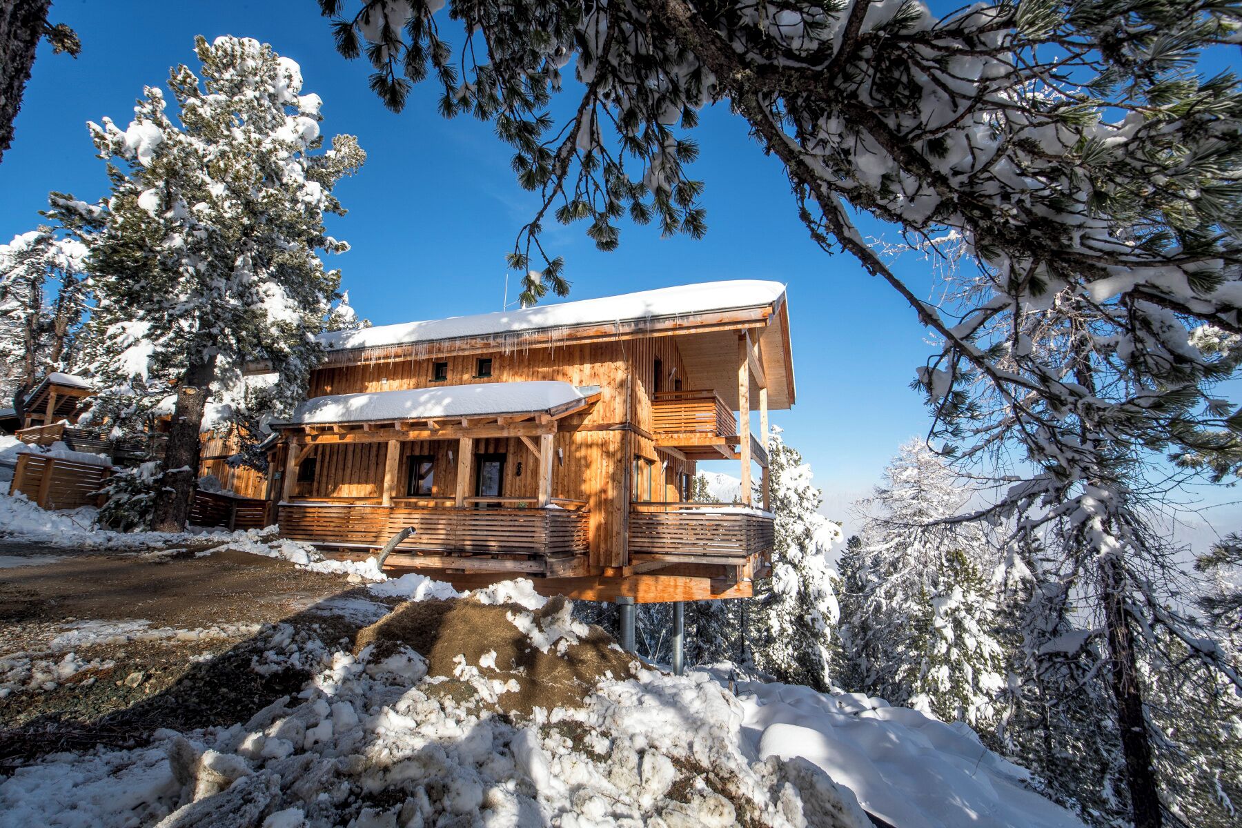 Una baita di legno con un balcone, circondata da alberi innevati.