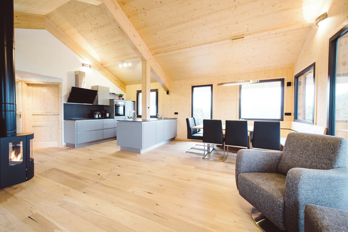A modern kitchen with a central island, a dining area with a table and chairs, and a cozy seating area with a sofa.