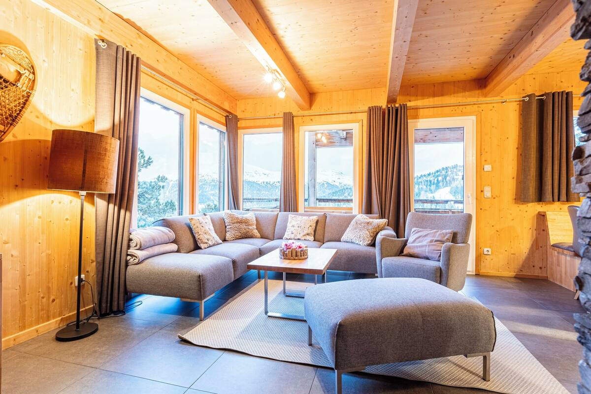 A cozy wooden interior with a sectional sofa, a small table, and a lamp.