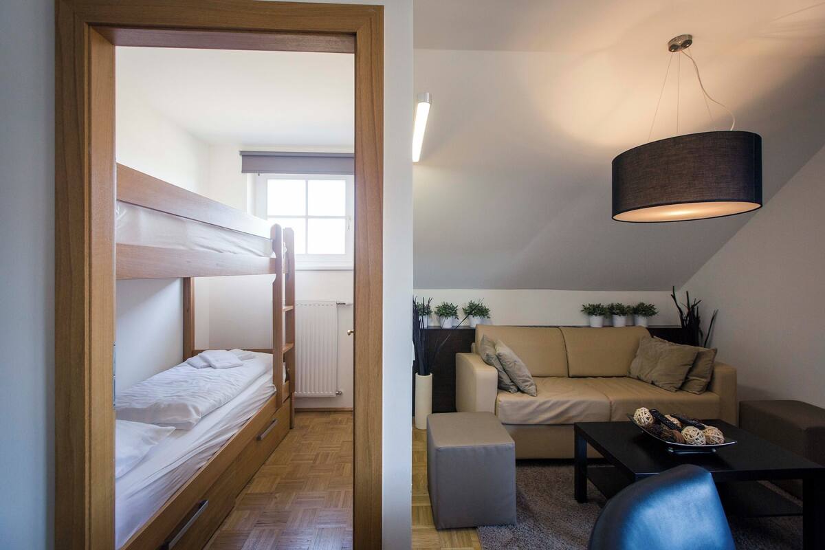 A compact room with a bunk bed, a sofa, a coffee table, and a hanging lamp.