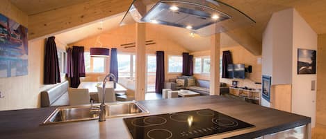 A modern kitchen with a central island, stainless steel sink, and a built-in stove.