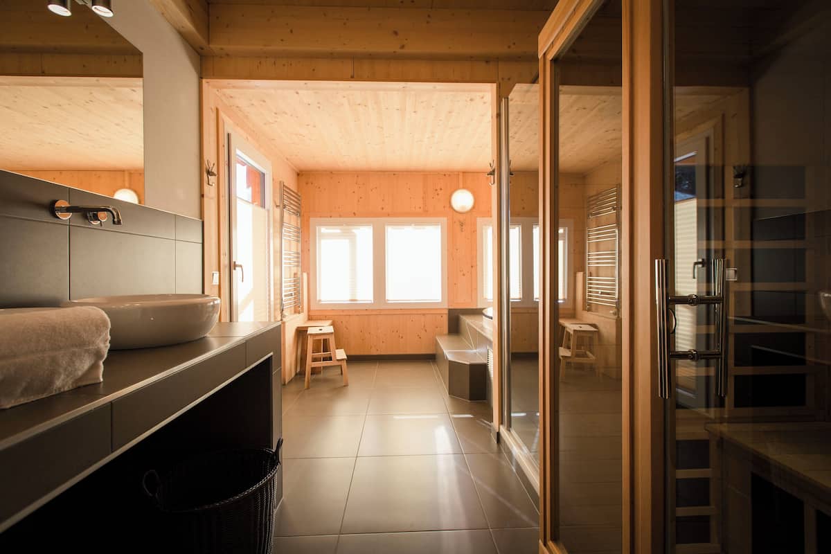 A modern bathroom with a wooden interior, a sink with a towel, and a small stool.