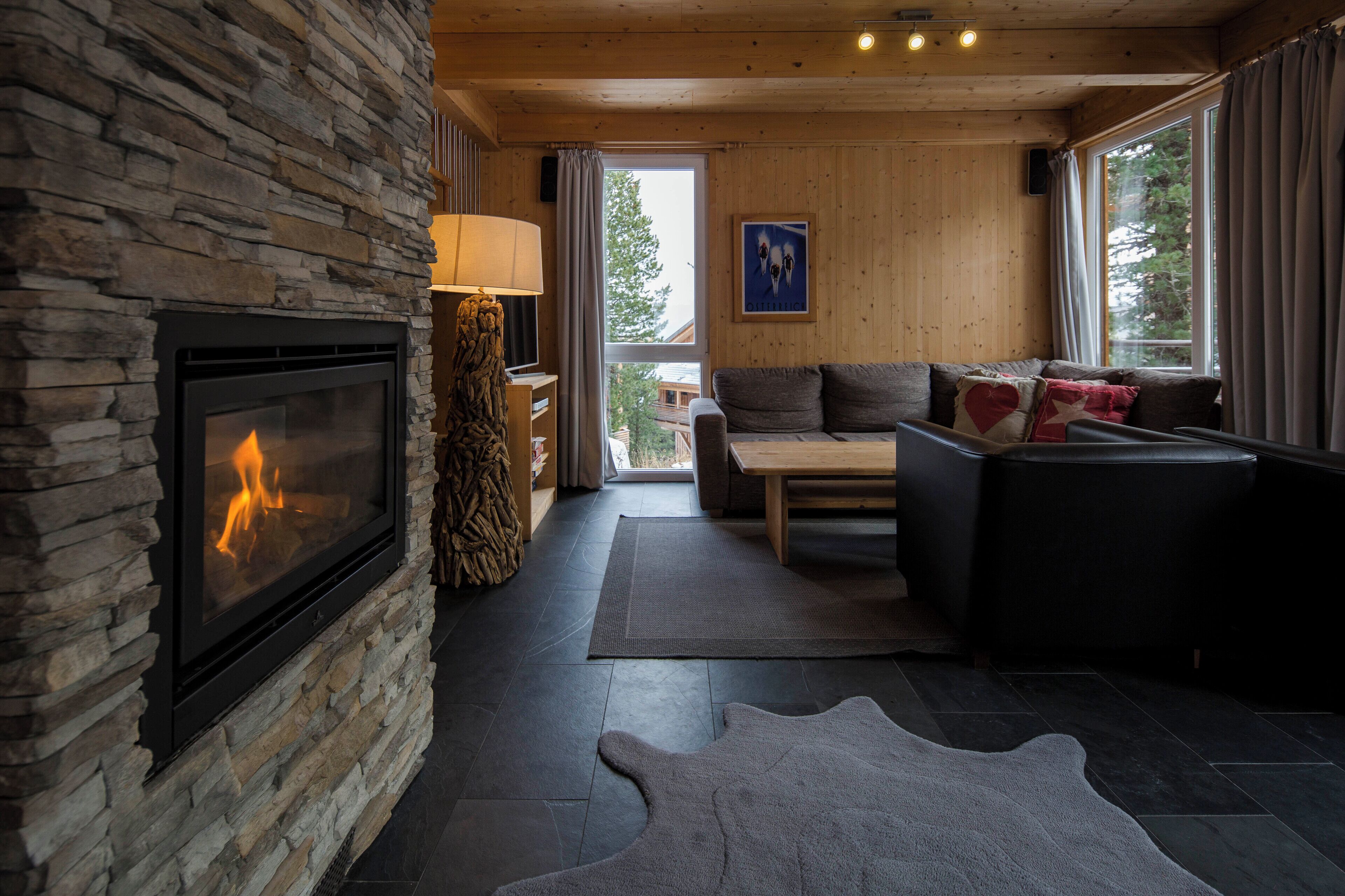 Una sala acogedora con chimenea de piedra, un sofá, una mesita de centro y una alfombra.