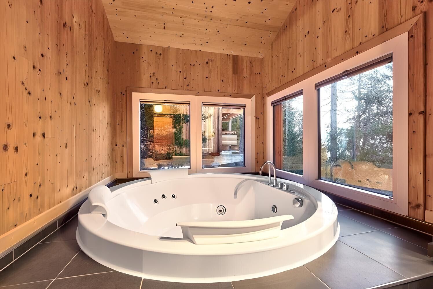 Un baño moderno con una bañera independiente, ventanas amplias y paredes de madera.