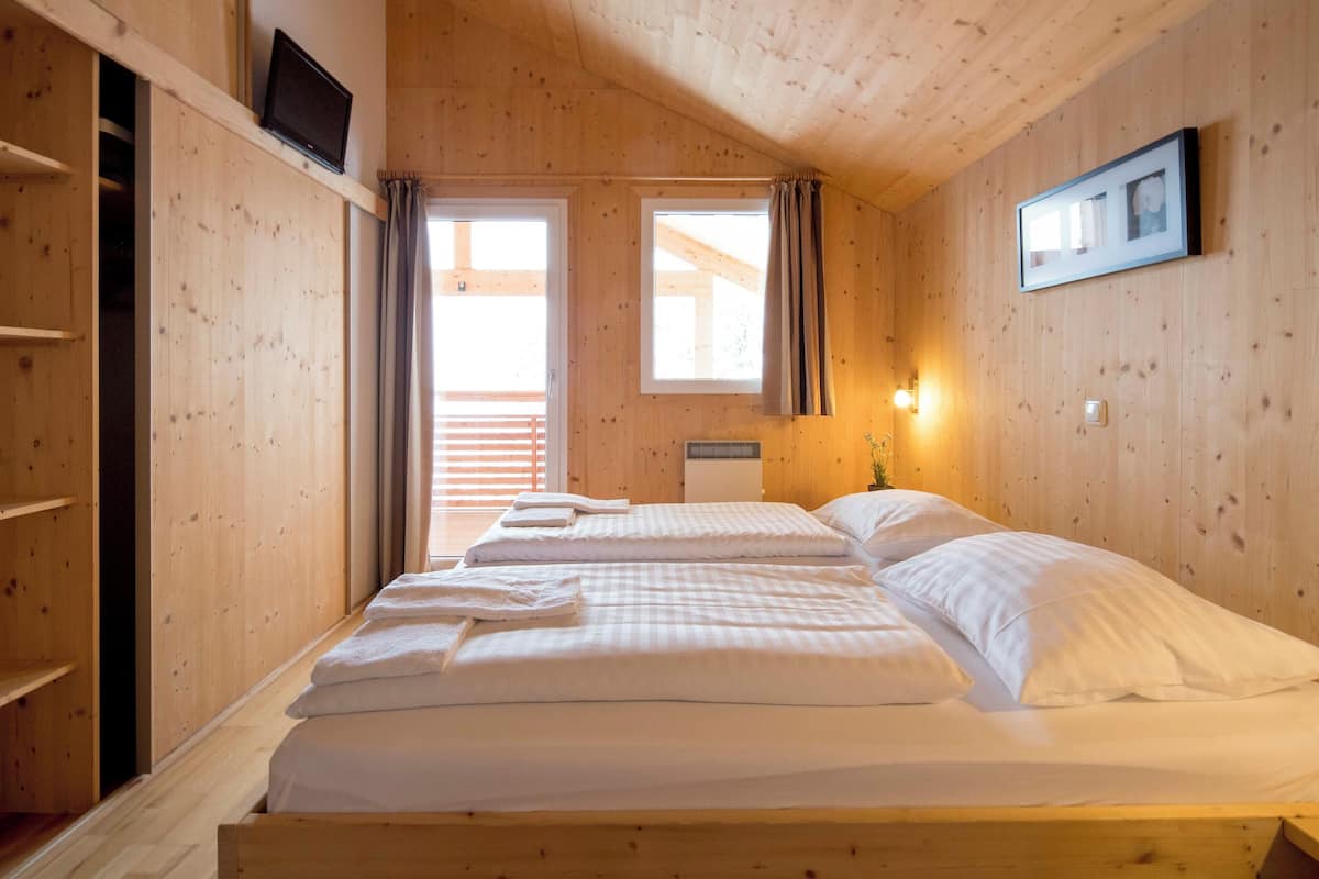 A wooden cabin room with two beds, a TV, and a framed picture on the wall.