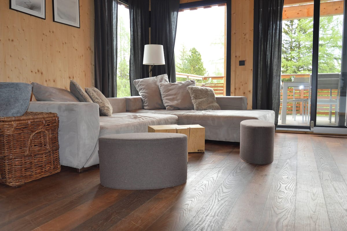 A modern living room with a sectional sofa, ottomans, a wicker basket, and a floor lamp.