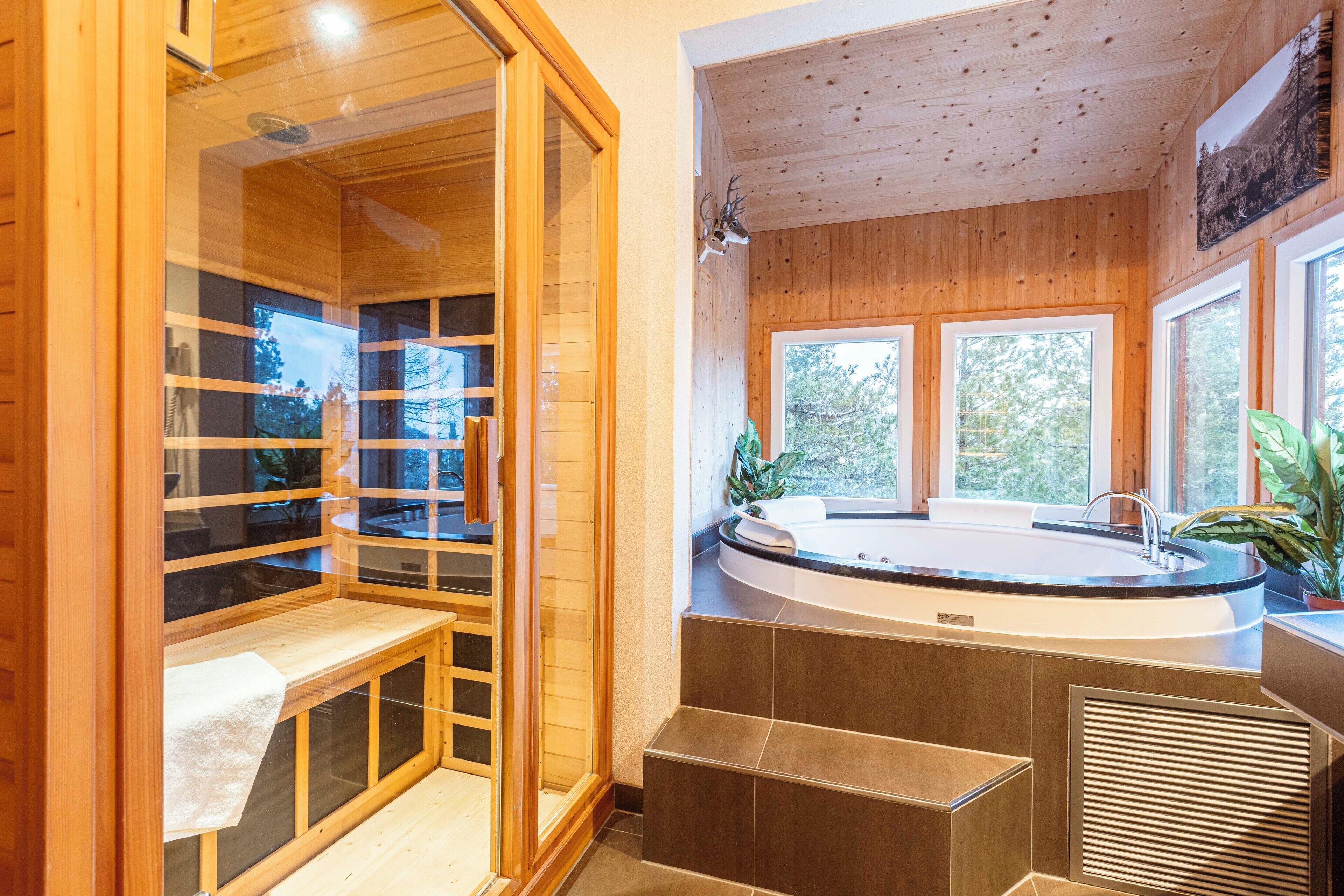 A wooden cabin interior with a sauna, a hot tub, and large windows offering views of the outdoors.
