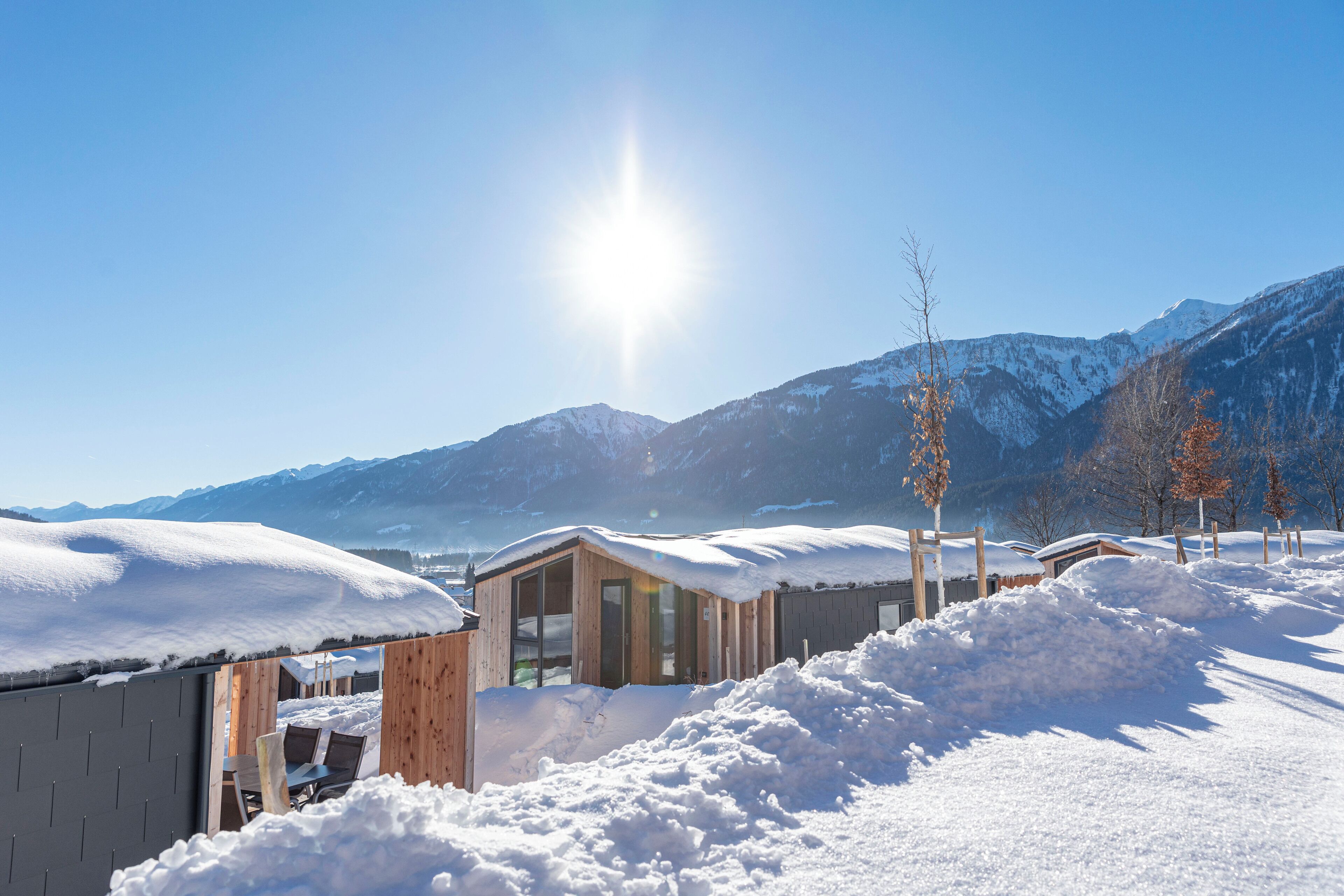 Un paysage enneigé avec un bâtiment en bois et des montagnes en arrière-plan.