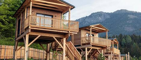 A wooden cabin with multiple levels, outdoor staircases, and a scenic mountain backdrop.