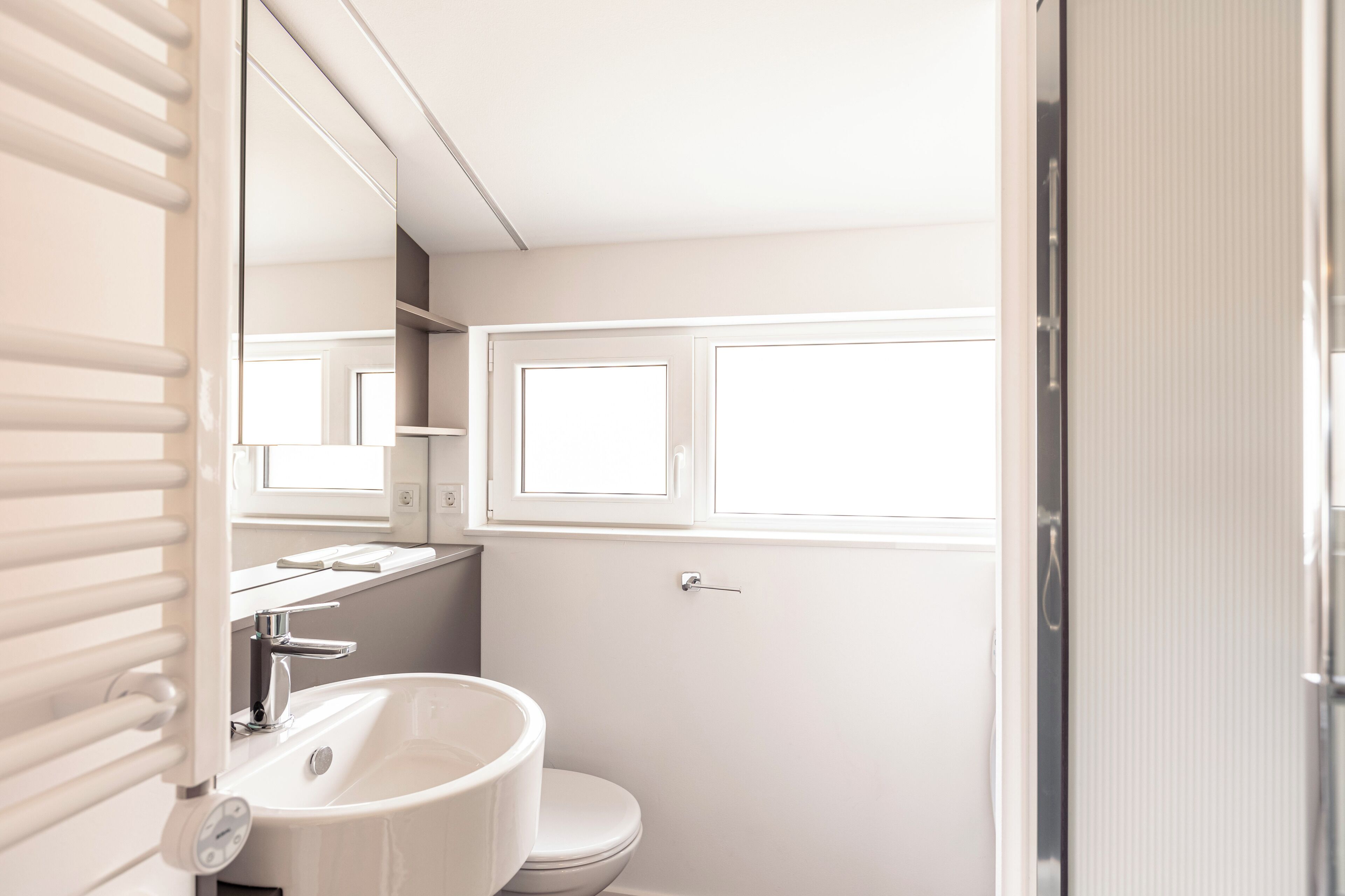 A bathroom with a white sink, a toilet, and a window above the toilet.